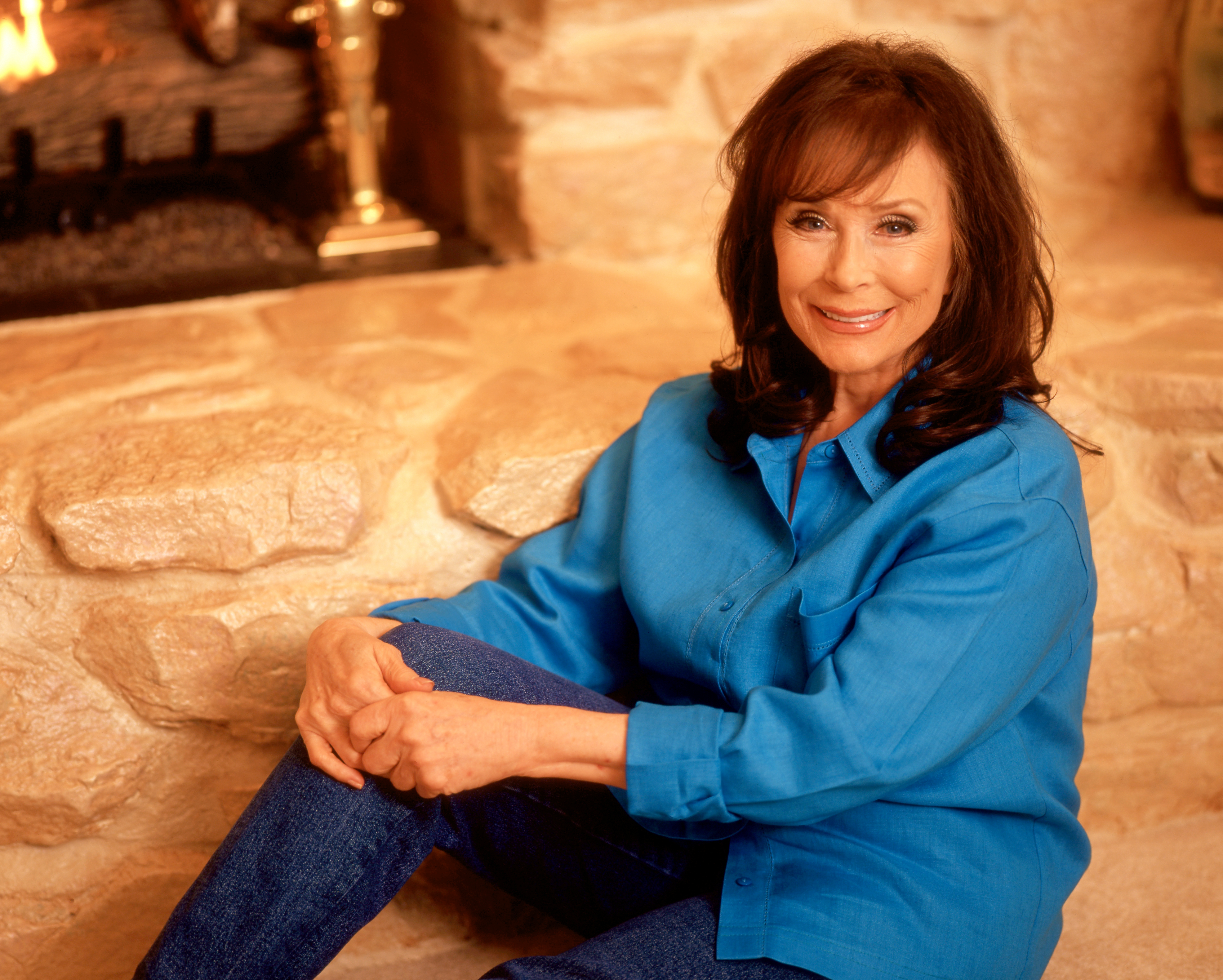 Loretta Lynn poses for a portrait in front of her fireplace in 1997 in Hurricane Mills, Tennessee. | Source: Getty Images
