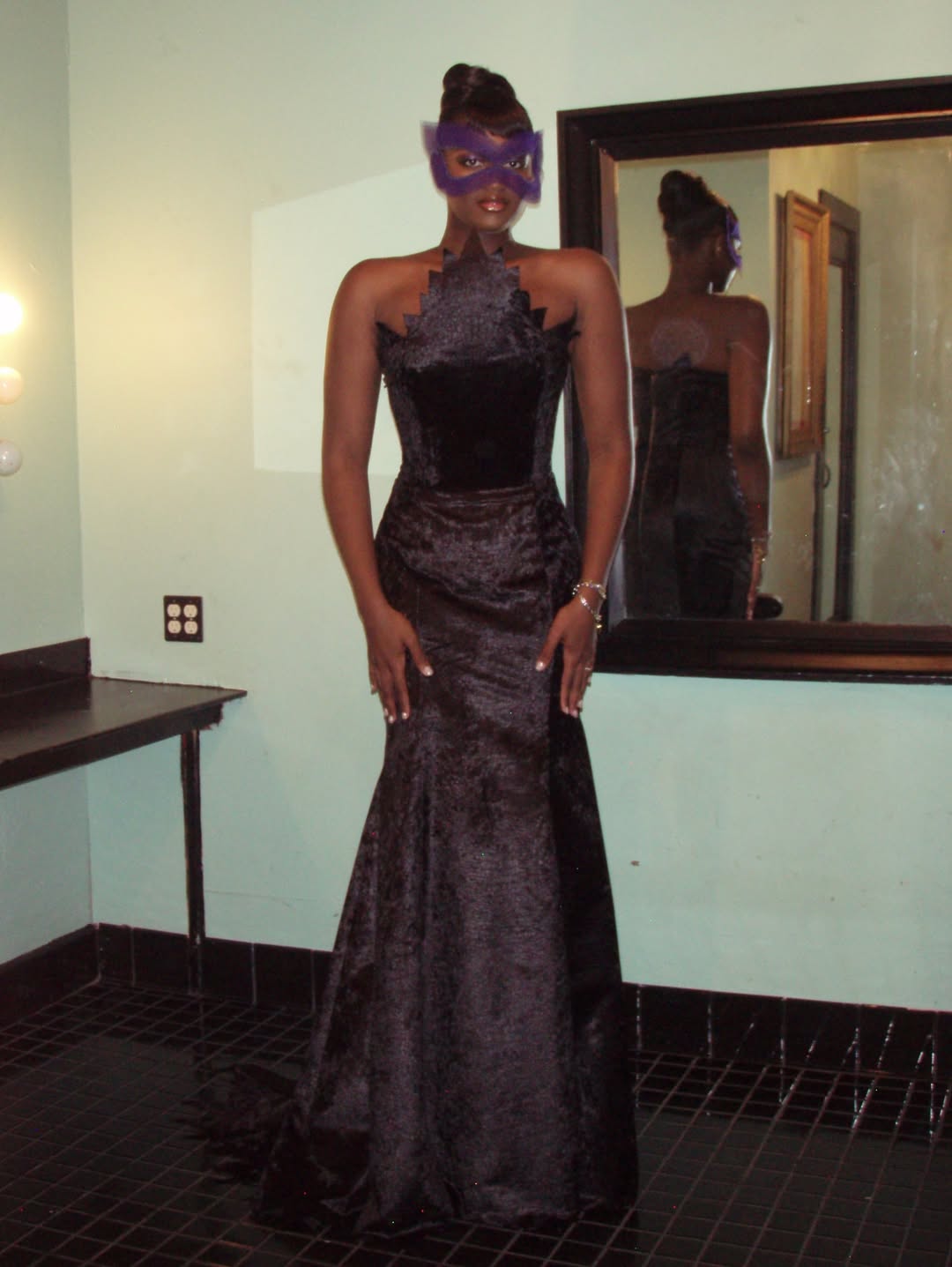 Zaya Wade poses in a black gown and purple masquerade mask, standing before a mirror that reflects the dramatic silhouette of her floor-length look. | Source: Instagram/zayawade