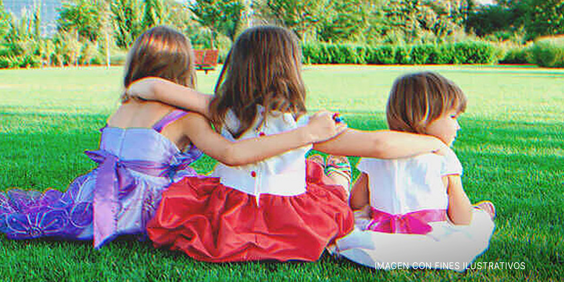 Tres niñas abrazadas sentadas sobre el pasto. | Foto: Shutterstock