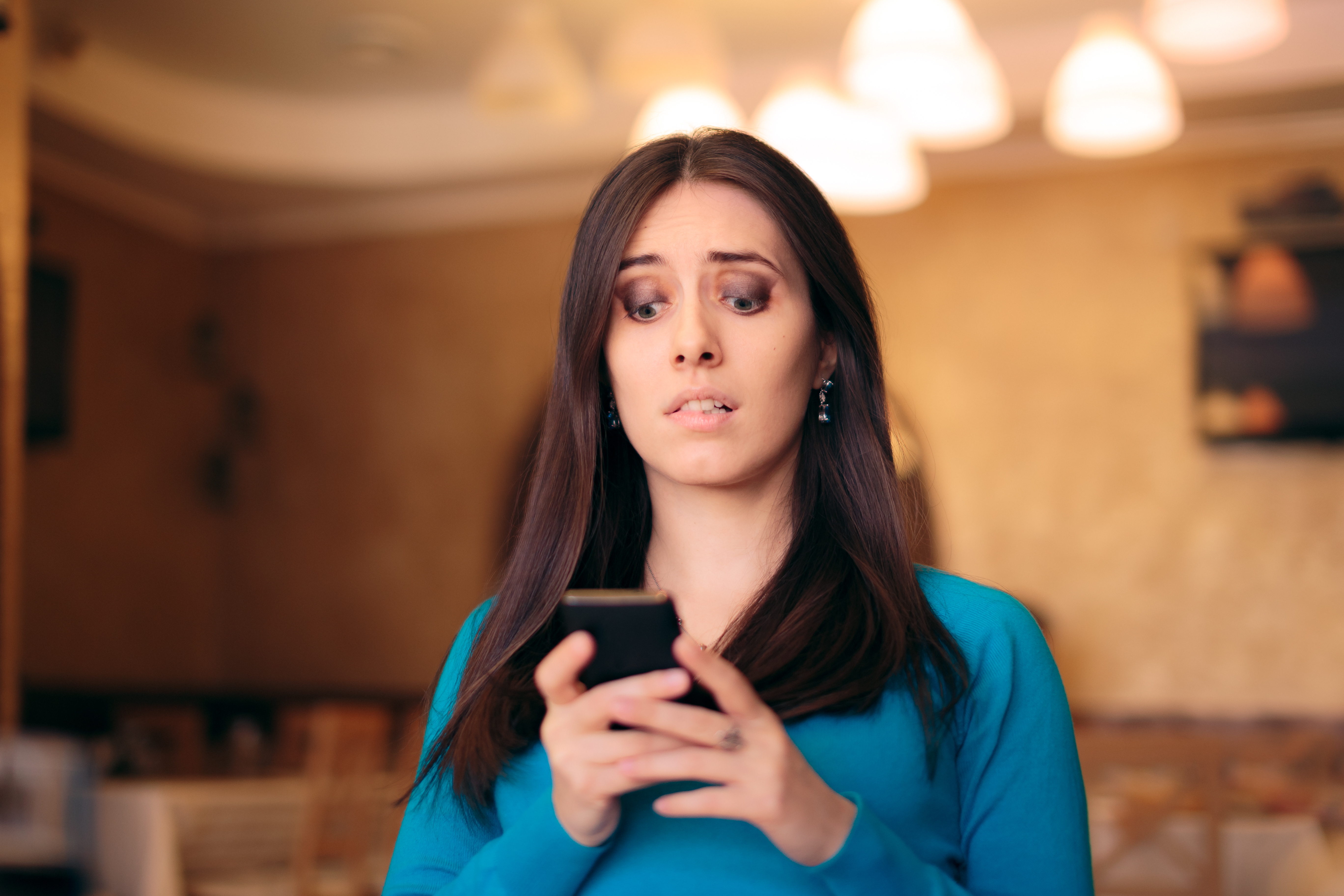 A woman looking shocked while on her phone | Source: Shutterstock