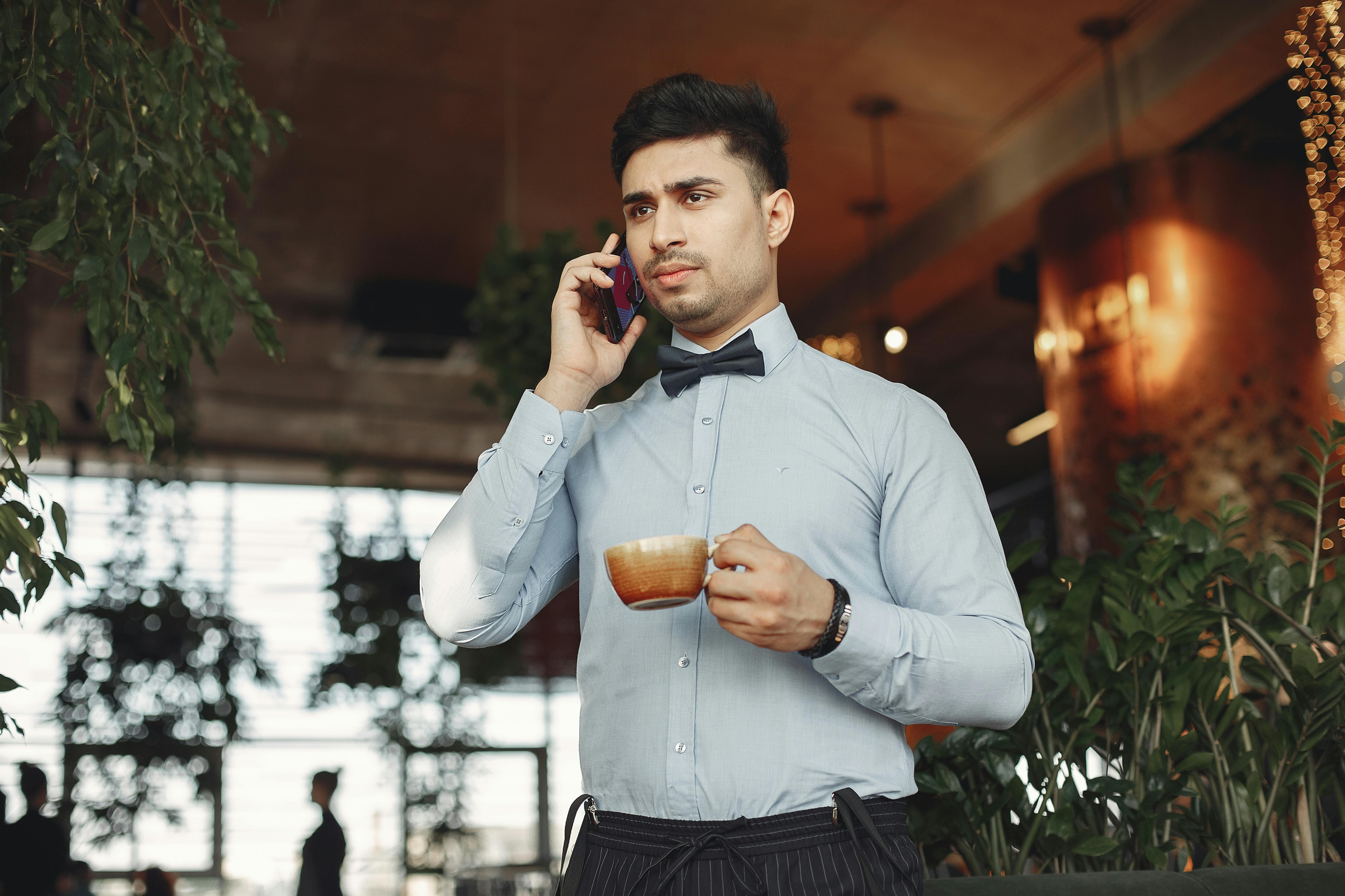 A serious-looking man talking on the phone while holding a beverage | Source: Pexels