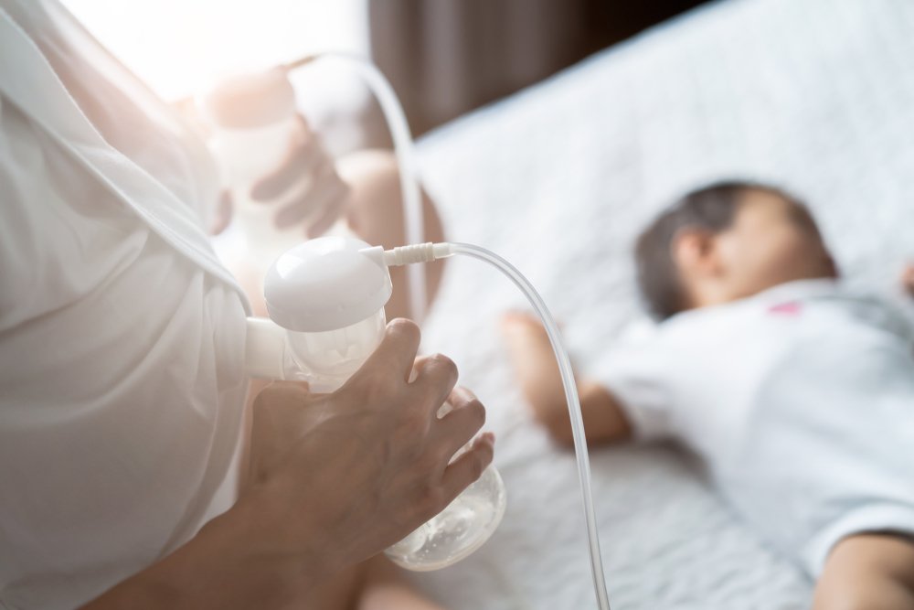 Ein Foto einer Mutter, die Muttermilch auf dem Bett im Schlafzimmer abpumpt. | Quelle: Getty Images
