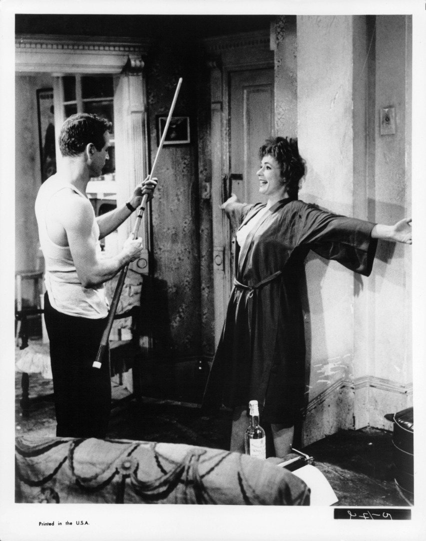 Paul Newman holding a pole stick as Piper Laurie leans against a wall will her arms held wide out in a scene from the film 'The Hustler', 1961 | Source: Getty Images