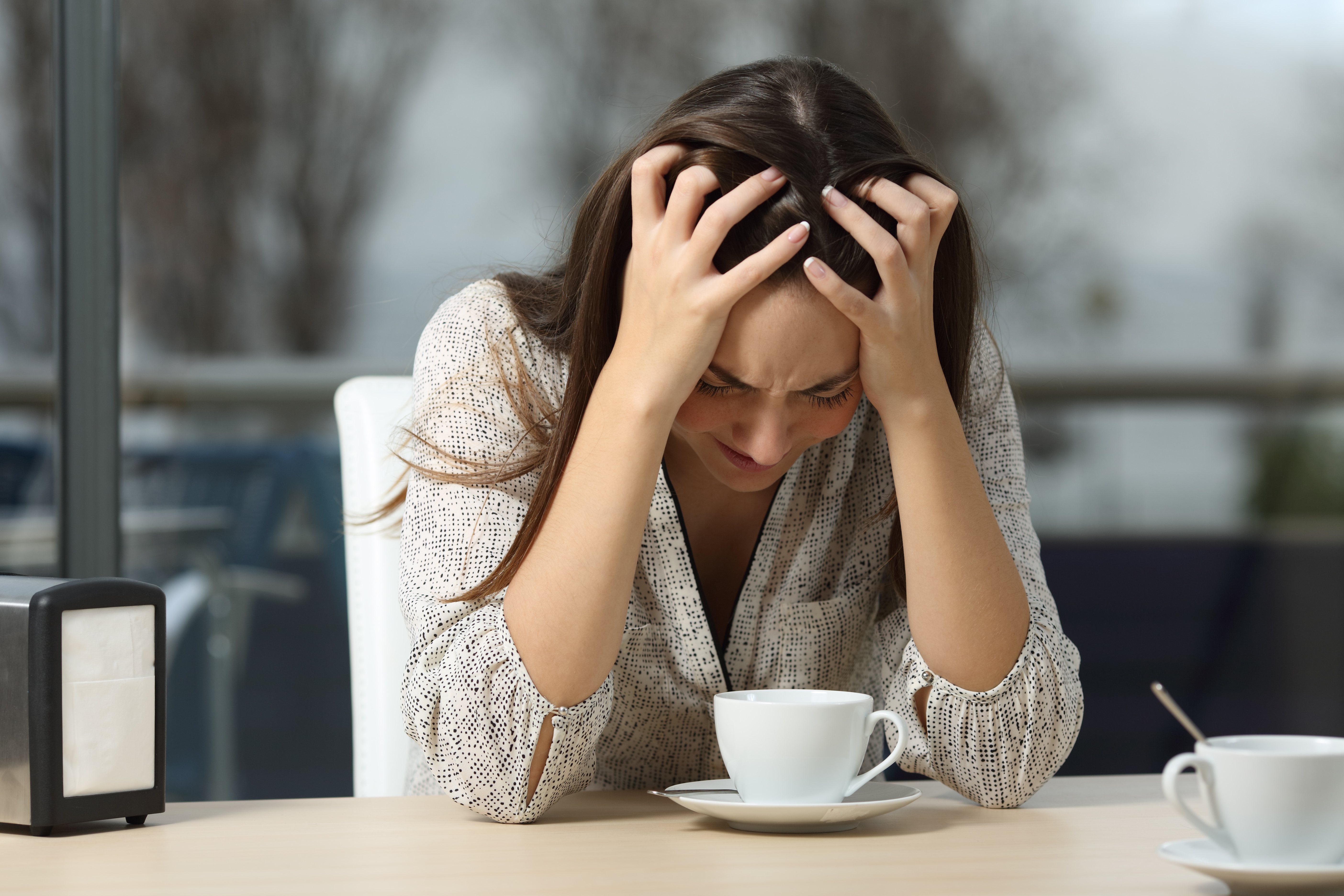 An upset woman sitting at a table | Source: Shutterstock