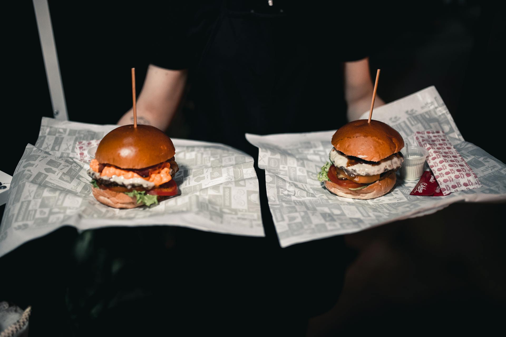 A waiter carrying two burgers | Source: Pexels