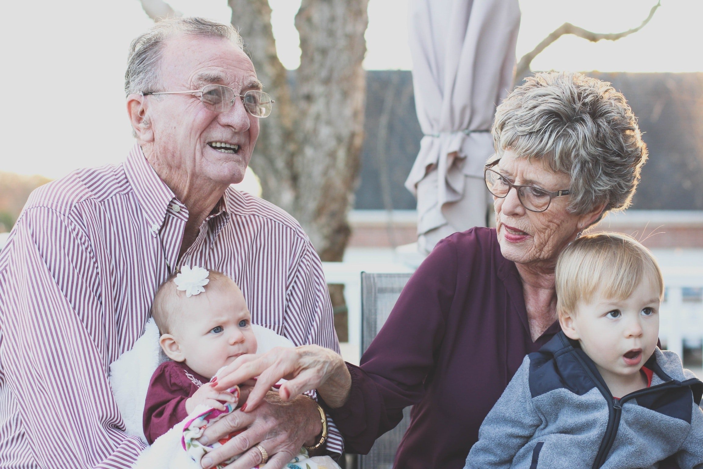 An elderly couple is pictured with two little ones. | Source: Pexels