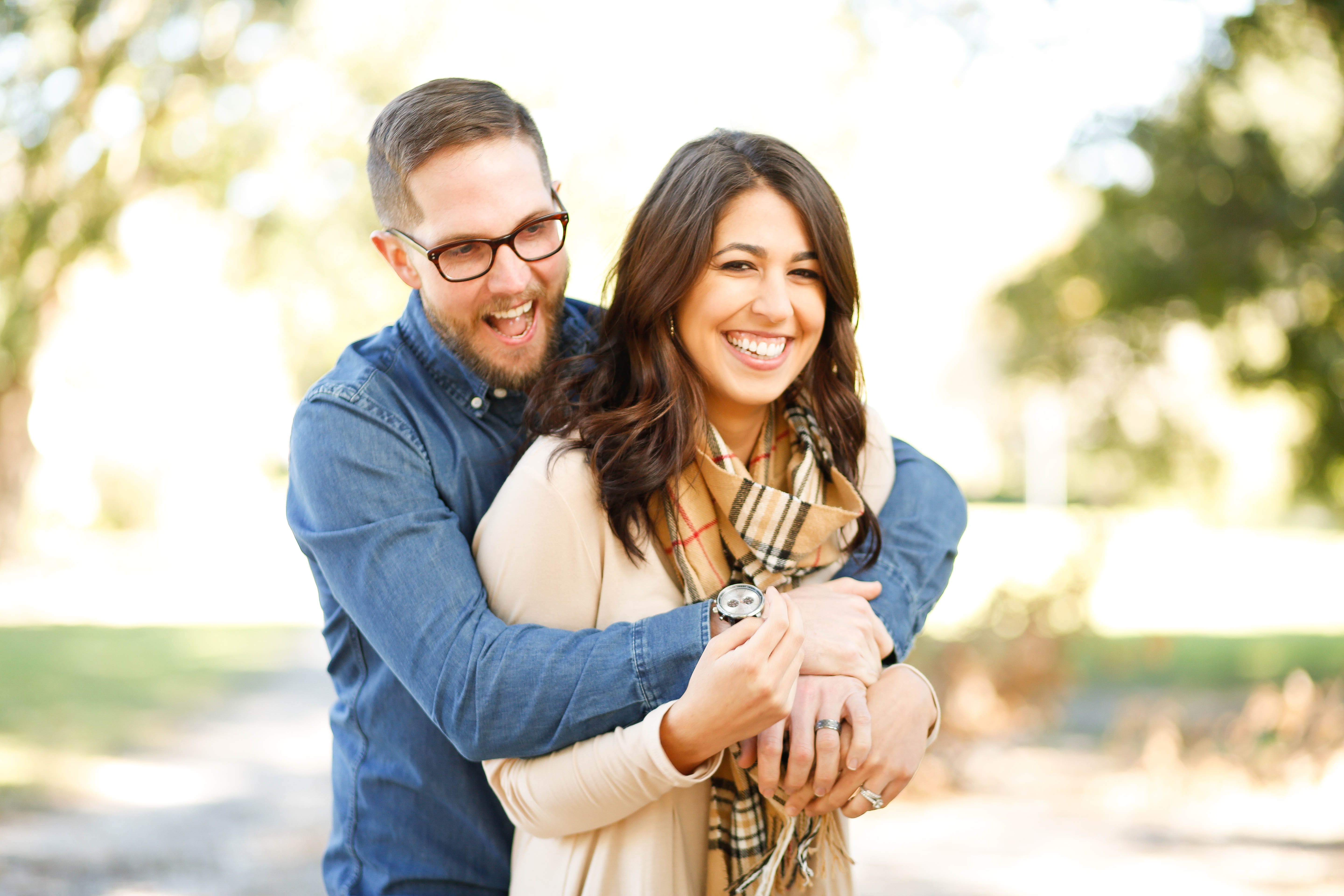 A couple smiling while the man embraces the woman from behind | Source: Pexels