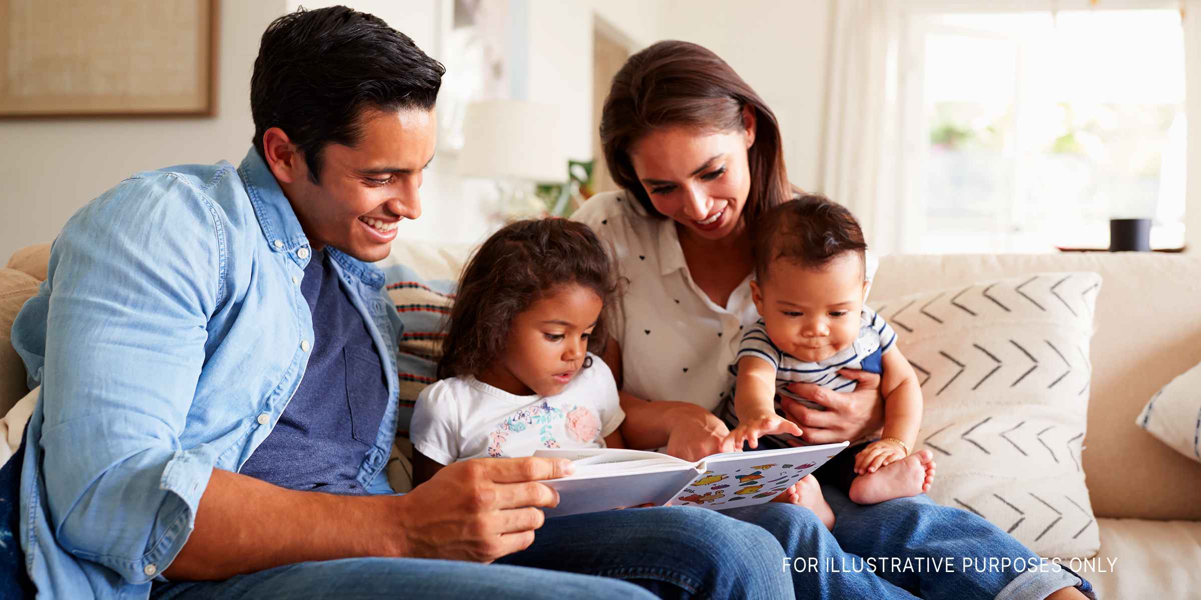 A biracial family sitting on a sofa reading | Source: Shutterstock
