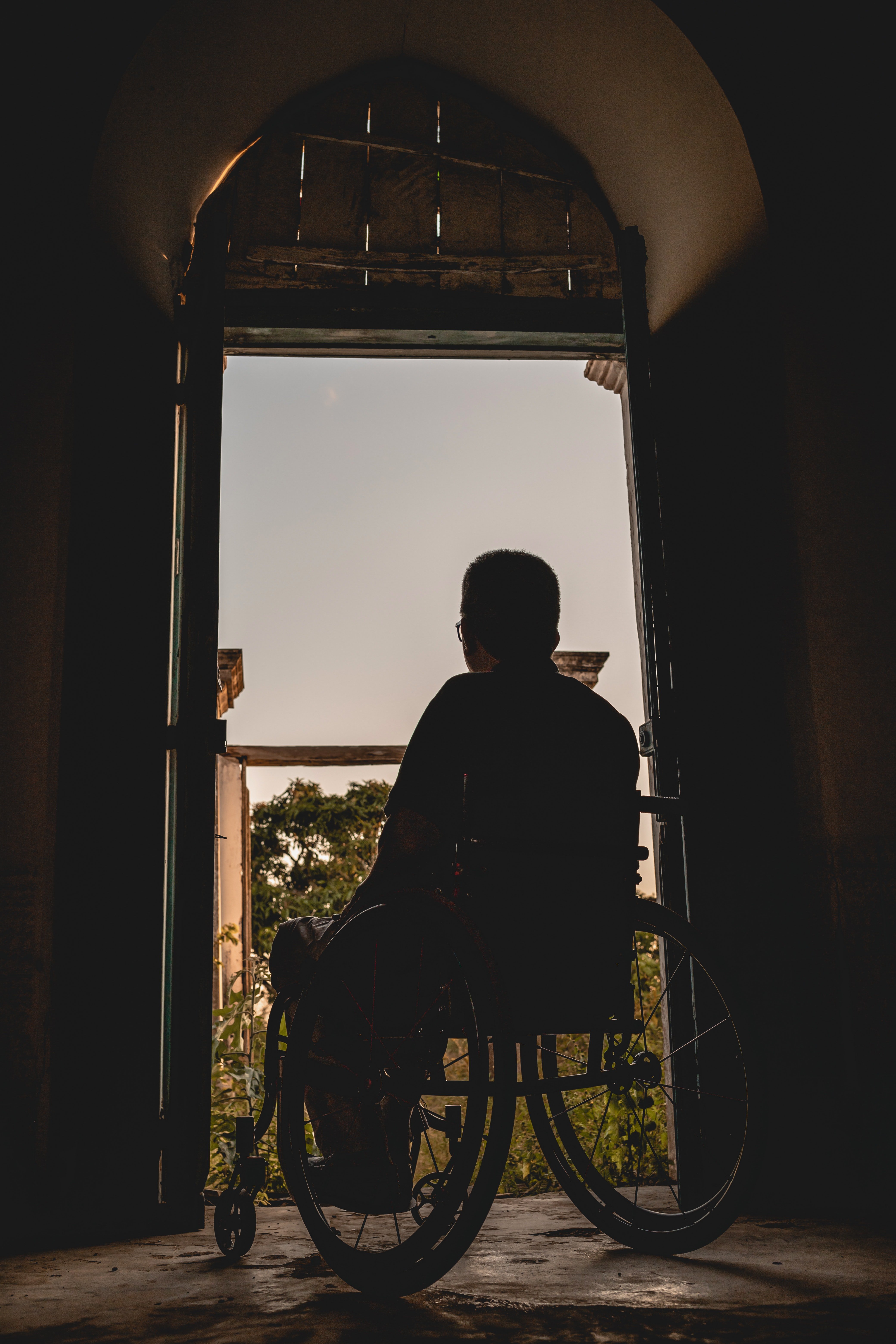 Un hombre en una silla de ruedas mirando a través de una ventana. | Foto: Pexels