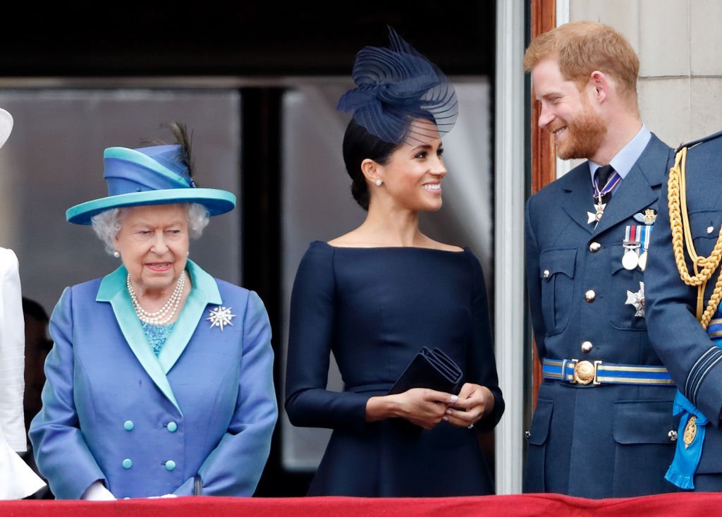 Queen Elizabeth, Meghan Markle and Prince Harry stand on the balcony at Buckingham Palace to watch a flypast that marked the centenary of the Royal Air Force on July 10, 2018, in London, England | Source: Max Mumby/Indigo/Getty Images