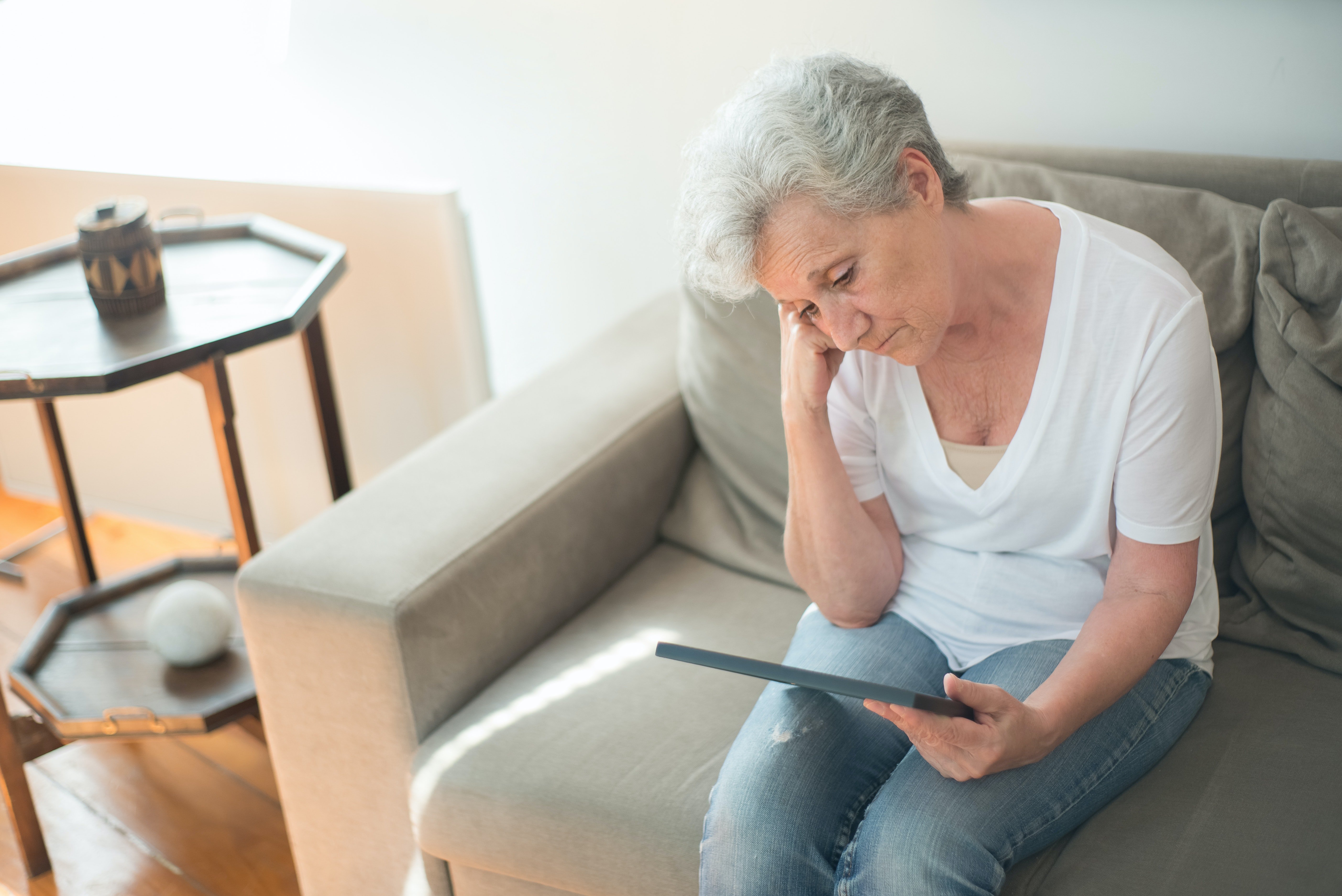 Anciana mira con tristeza la pantalla de su equipo electrónico. | Foto: Shutterstock