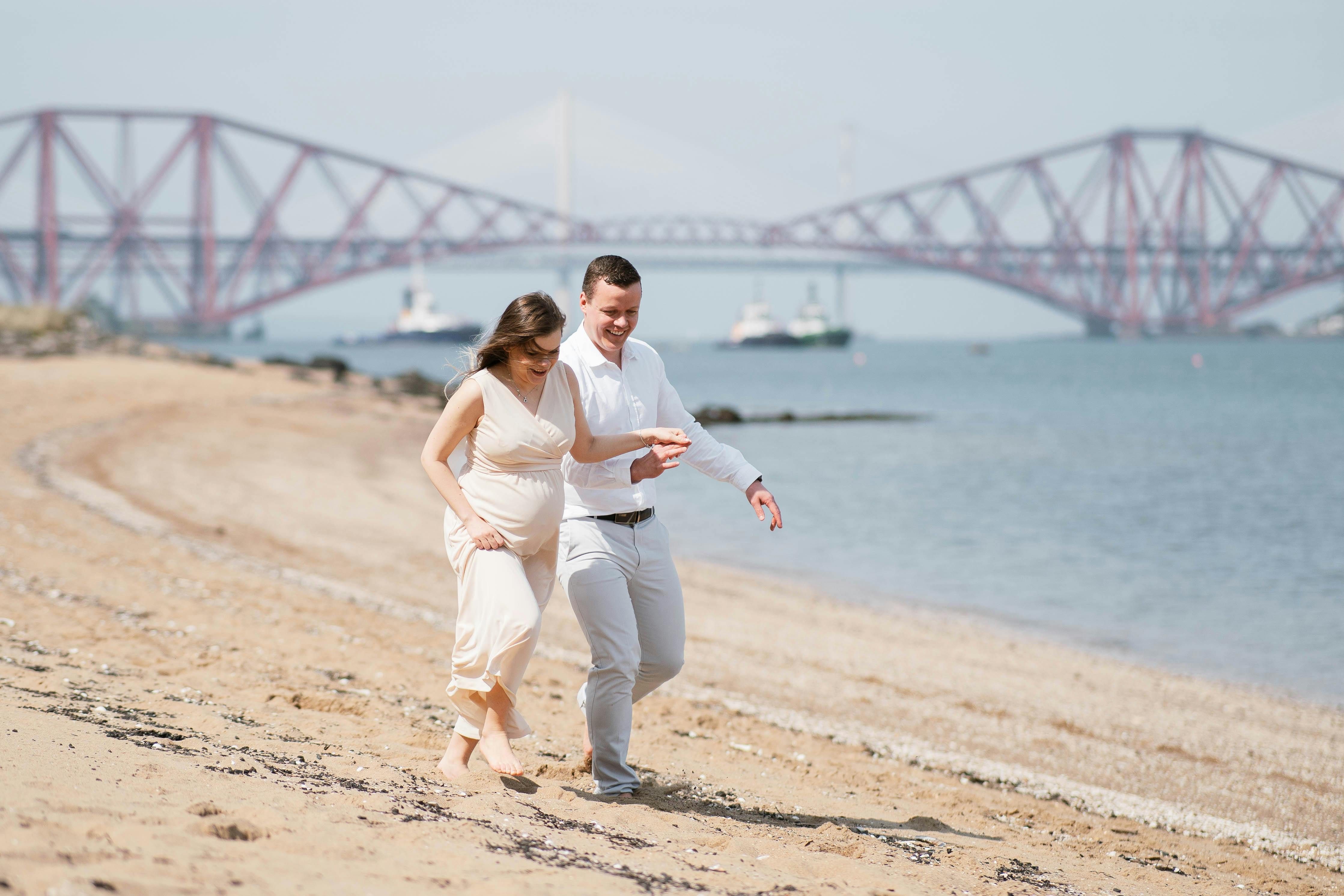 A pregnant woman and her partner walking along a beach | Source: Pexels