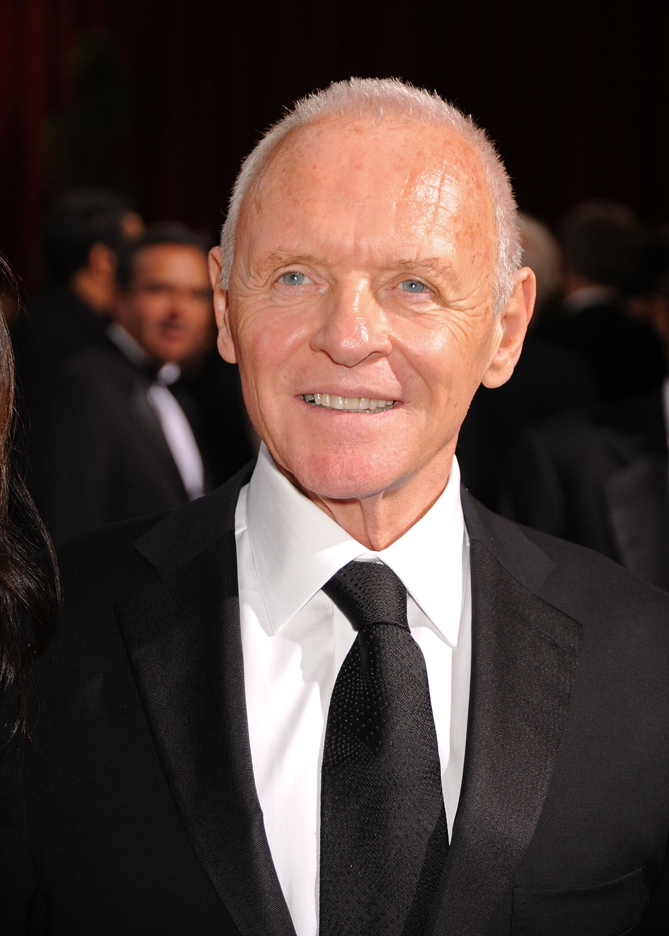 At the 81st Annual Academy Awards, Anthony Hopkins radiates timeless sophistication. Dressed in a sleek black tuxedo paired with a matching tie, his confident smile reflects both grace and gravitas. The soft glow of the event lights captures his enduring charisma amidst Hollywood's finest.