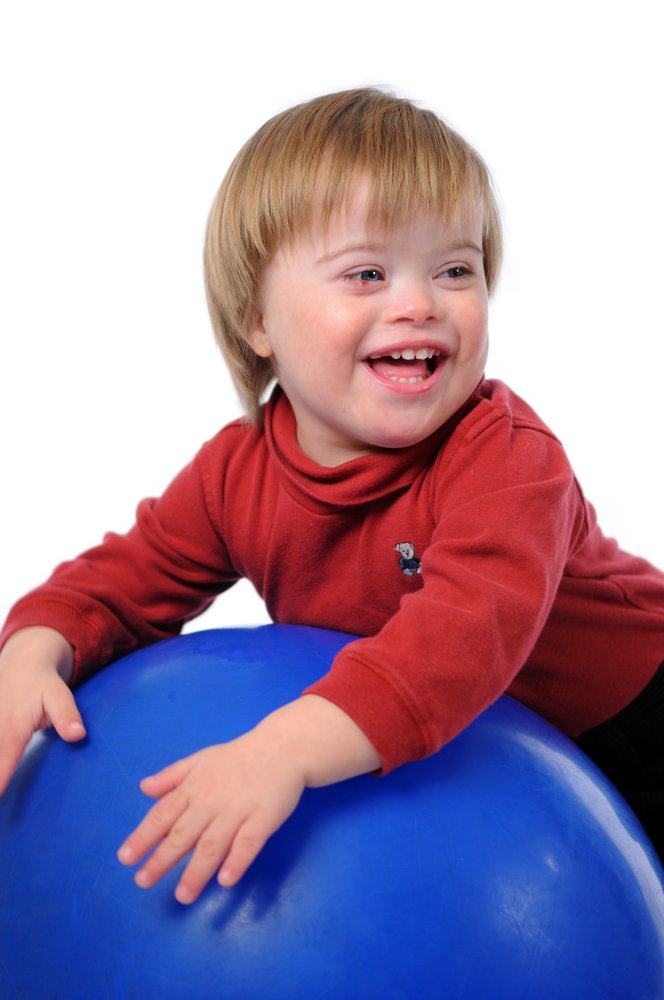 Niño con síndrome de Down sonriente jugando con una pelota. Fuente: Shutterstock. Niño con síndrome de Down sonriente jugando con una pelota. Fuente: Shutterstock.