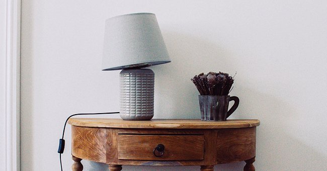 Lamp resting on a wooden table | Photo:  unsplash.com/Michal Balog