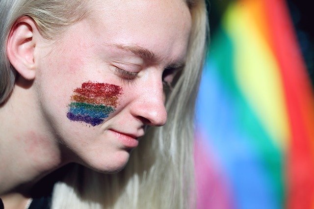 A woman attends a LGBT pride parade with the rainbow flag painted with glitter on her face. I Image: Getty Images.