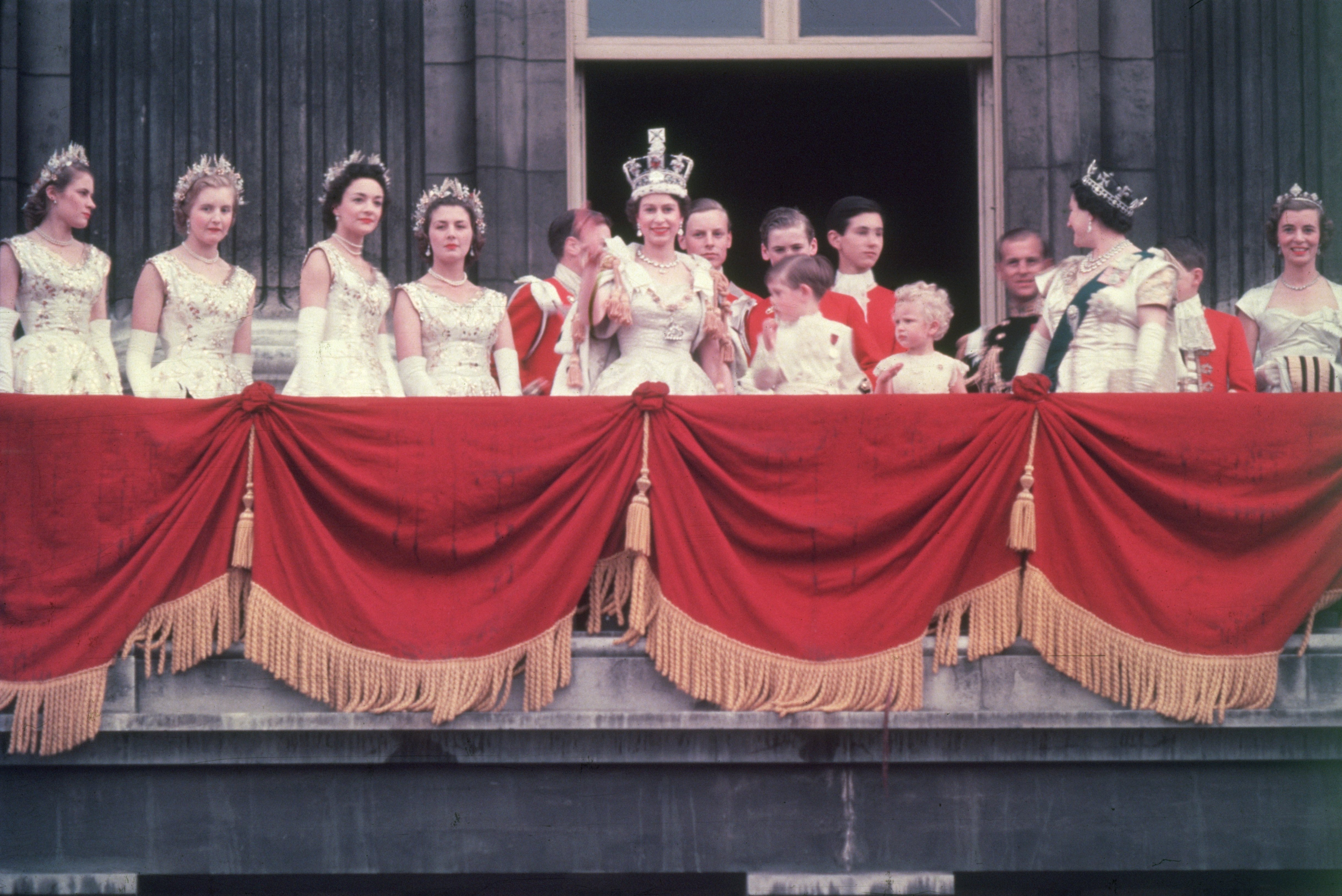  The newly crowned Queen Elizabeth II waves to the crowd from the balcony at Buckingham Palace. Her children Prince Charles and Princess Anne stand with her in 1953 | Photo: Getty Images