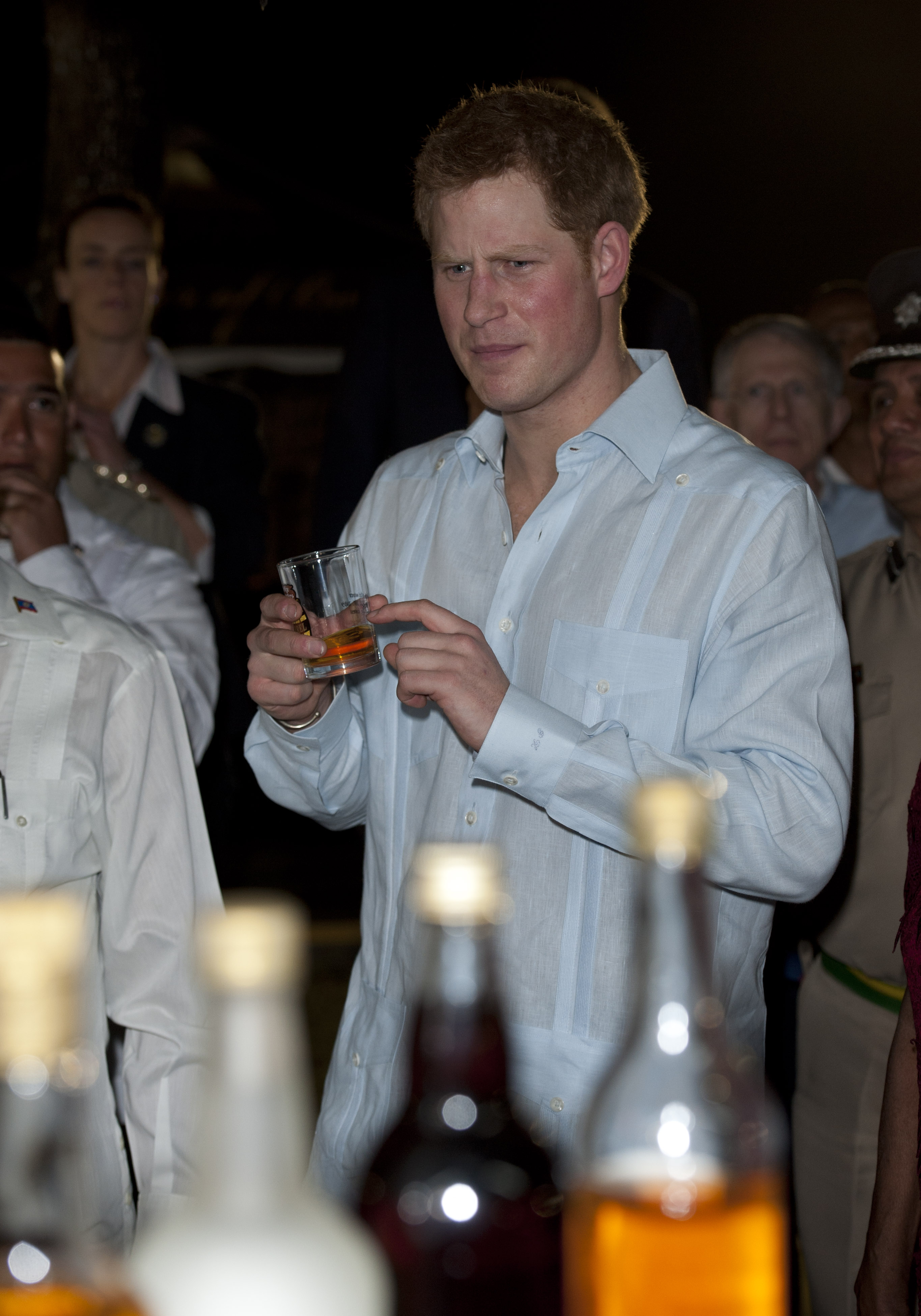 On the first day of his official visit to Belize on March 1, 2012, Prince Harry was photographed sampling a local drink during a street party in Belmopan. Surrounded by onlookers and dignitaries, including the Governor General, Sir Colville Young, the prince wore a measured expression as he lifted the glass — a snapshot of a man still known for his mischief, but increasingly stepping into the role of global representative.