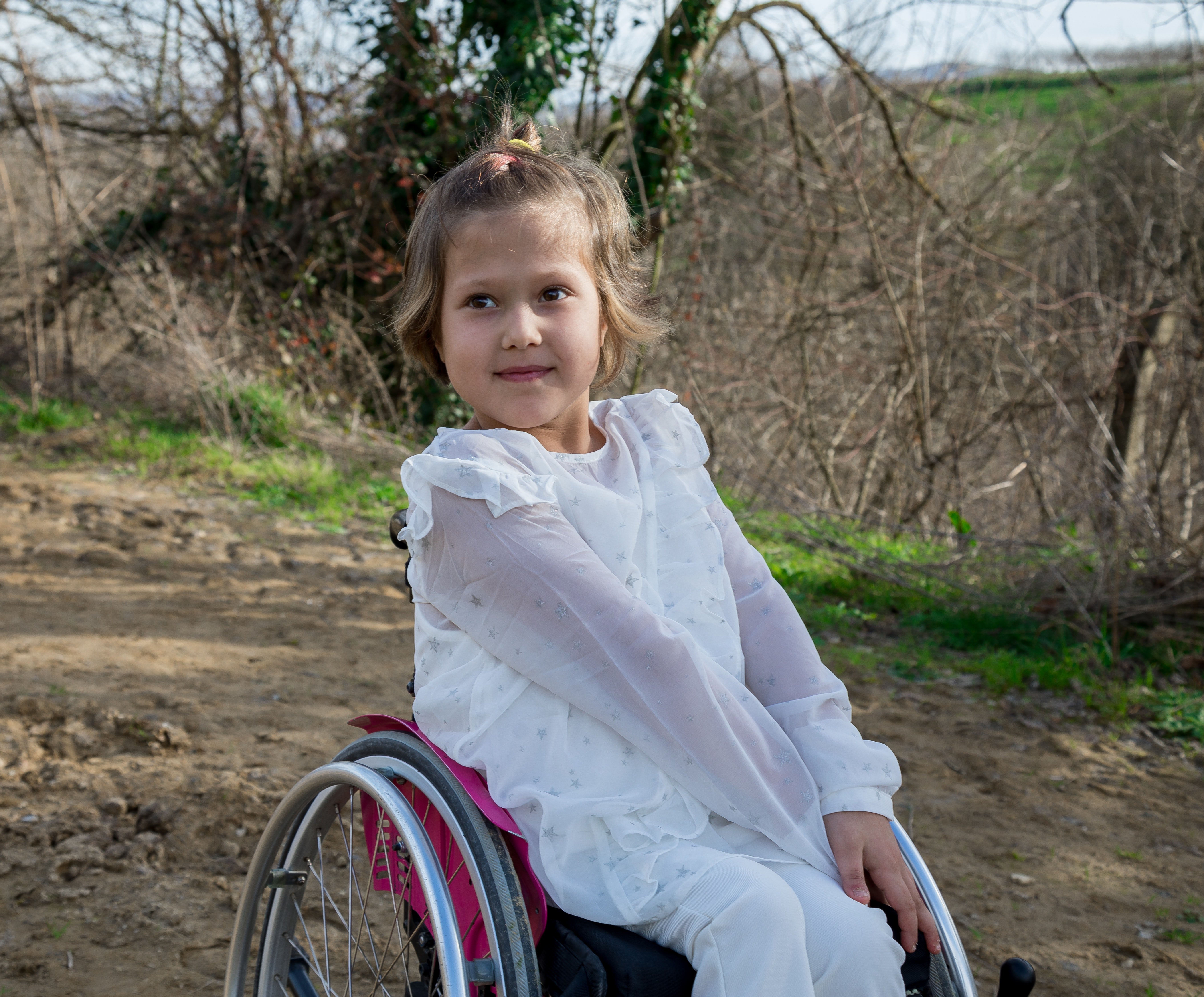 Una niña en silla de ruedas sonriendo. | Foto: Pexels