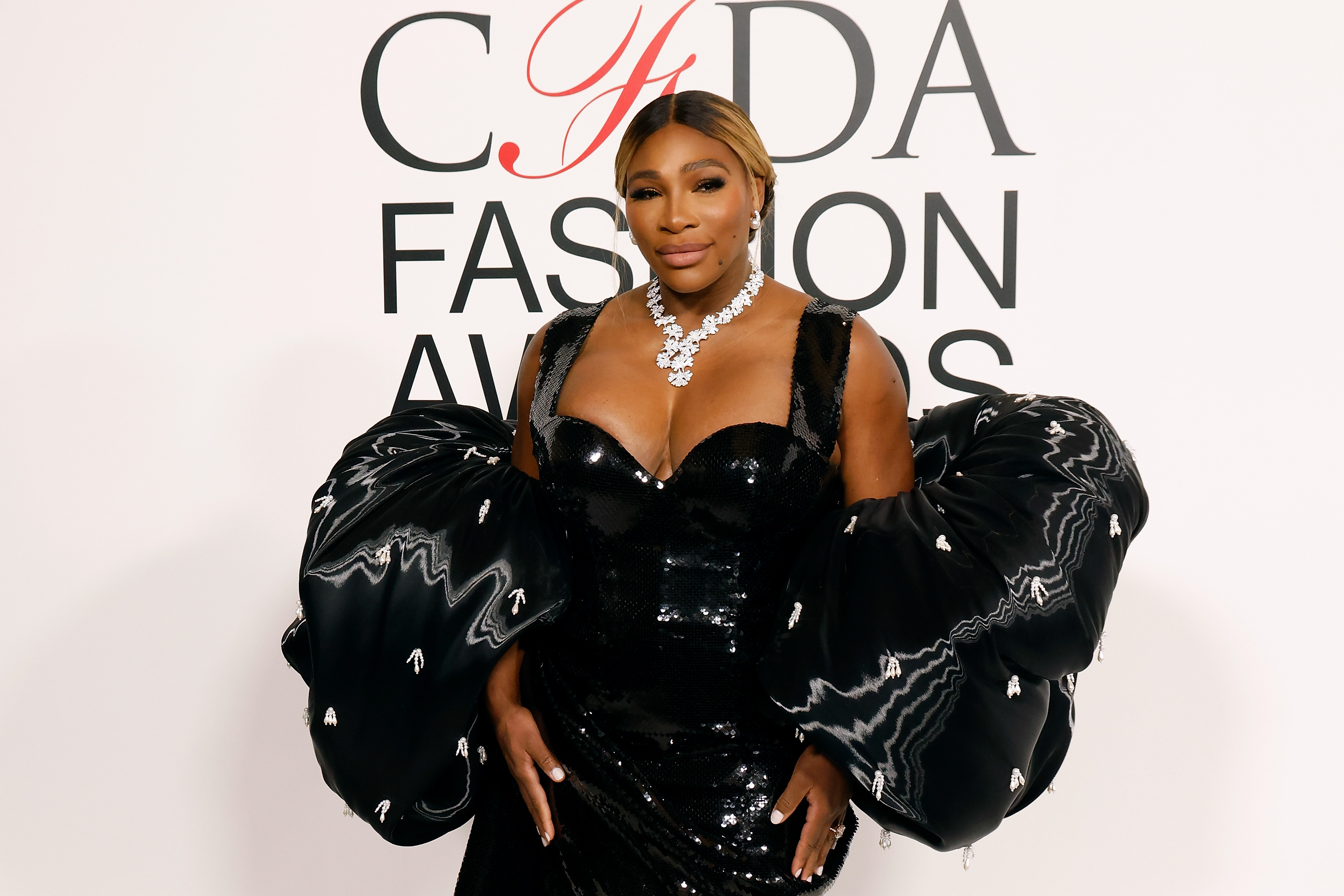 At the CFDA Awards in November 2023, in New York City, Serena Williams wore a dramatic black gown with voluminous sleeves and a long train. Her look was completed with a sleek updo and bold eye makeup.