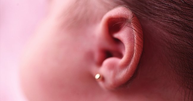 Side view of a young girl's ear piercing. | Photo: Shutterstock 