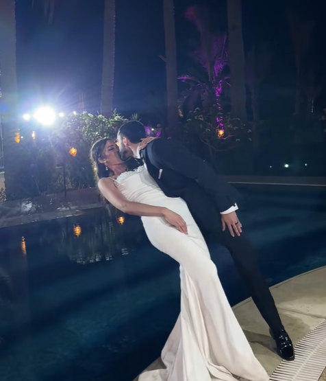 The bride and groom share a kiss before he lets go of her and slightly pushes her into the pool, from a July 2025 video post | Source: TikTok/emadjoe1