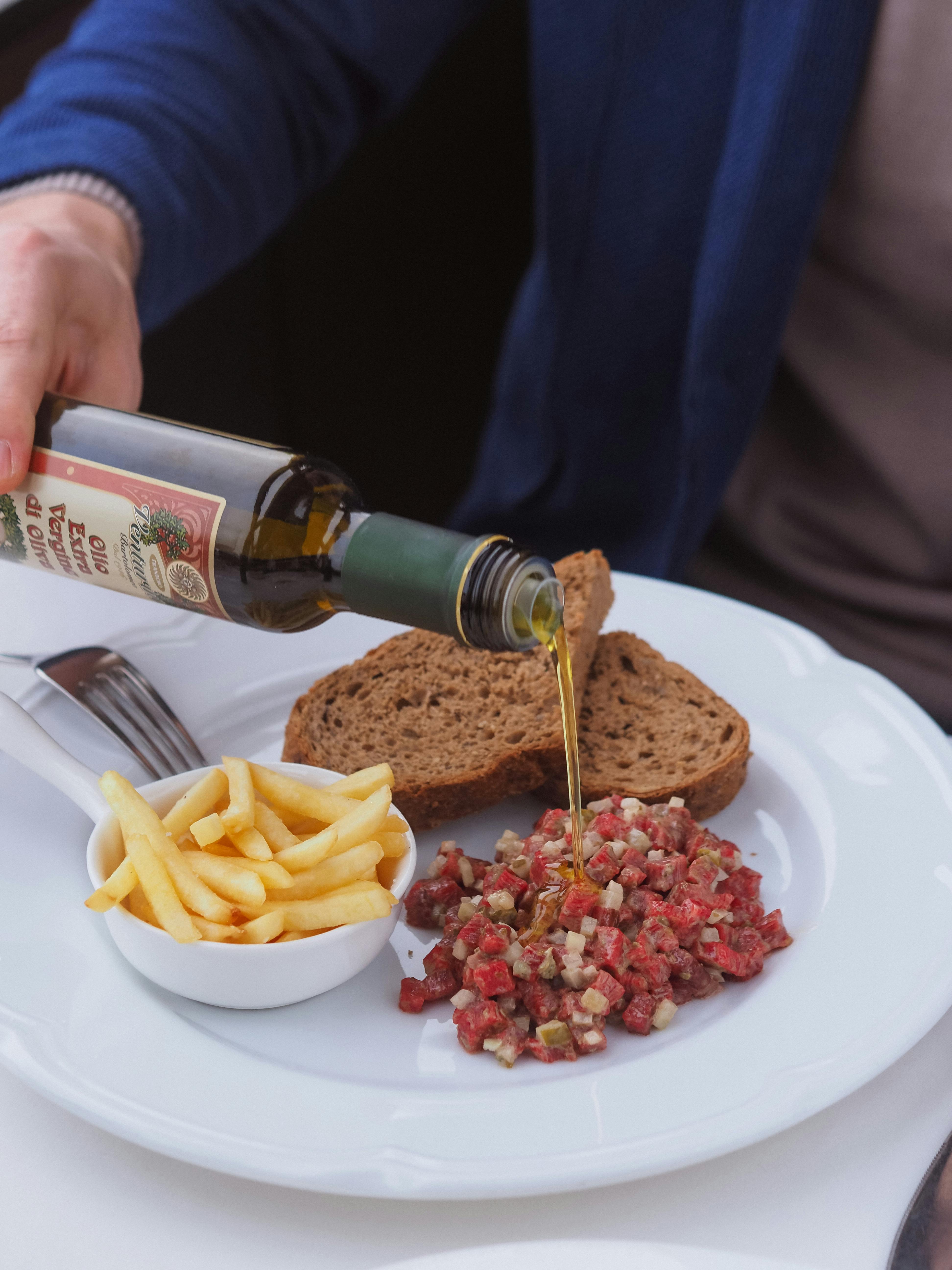 A person adding olive oil to their food | Source: Pexels