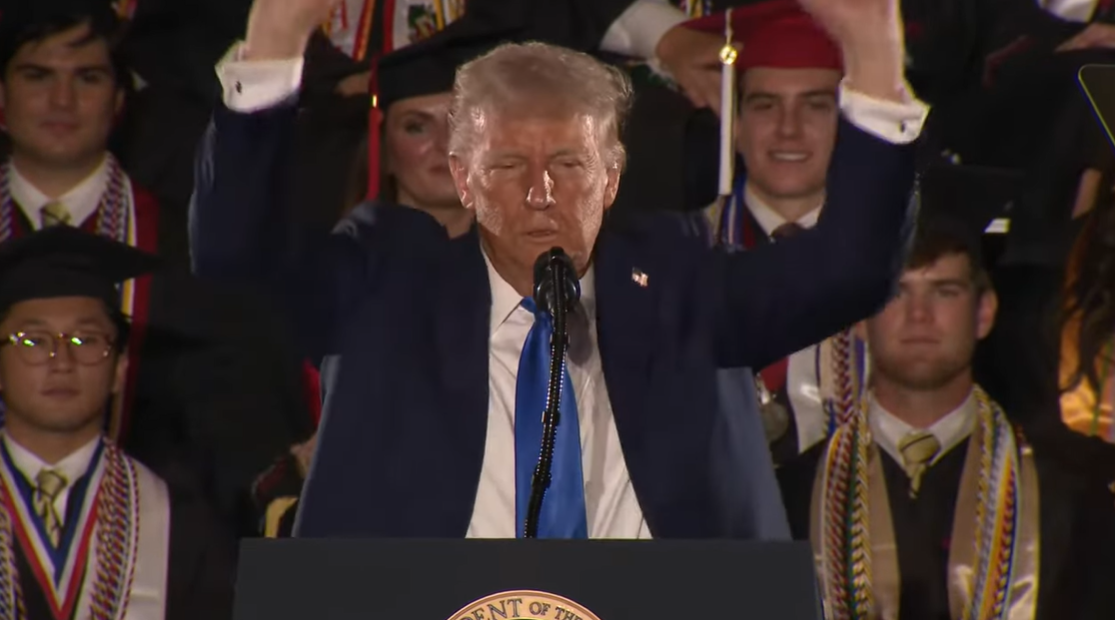 Donald Trump lifts his arms to mimic a weightlifter during the University of Alabama's commencement ceremony in Tuscaloosa | Source: YouTube/WhiteHouse