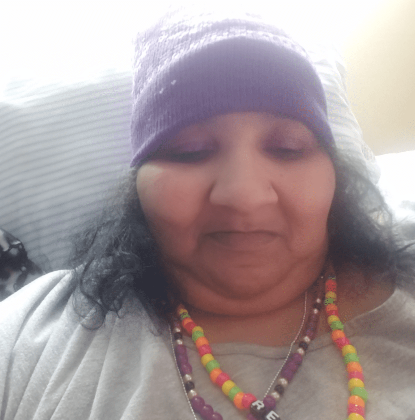 Pictured - A selfie of Renee Biran wearing a purple beanie with a gray shirt and multicolored necklaces | Source: Facebook/@reneebiran 