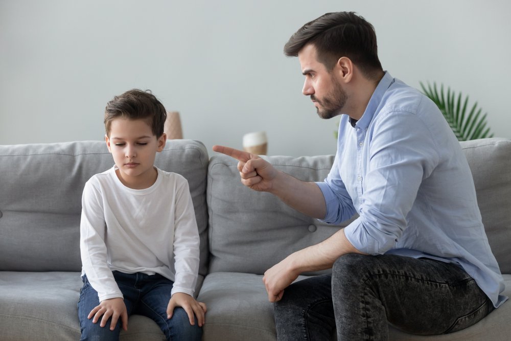 An angry father scolding and lecturing his sad preschool kid son. | Photo: Shutterstock