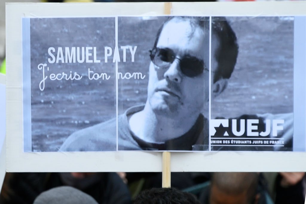 Une personne tient une pancarte avec le portrait du professeur d'histoire Samuel Paty alors que les gens se rassemblent sur la place de la République à Paris le 18 octobre 2020. | Photo : Getty Images