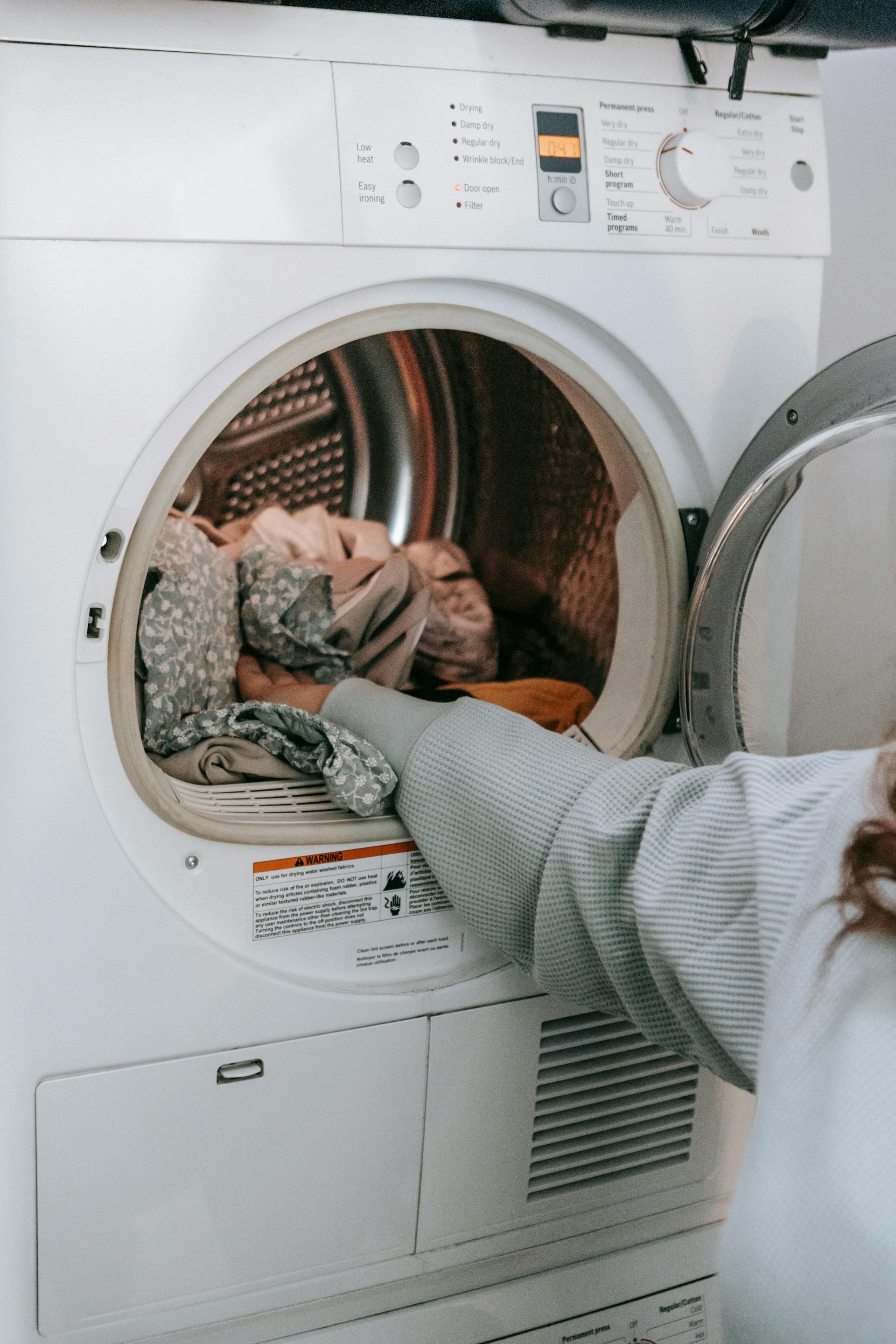 A woman loading clothes in a washing machine | Source: Pexels