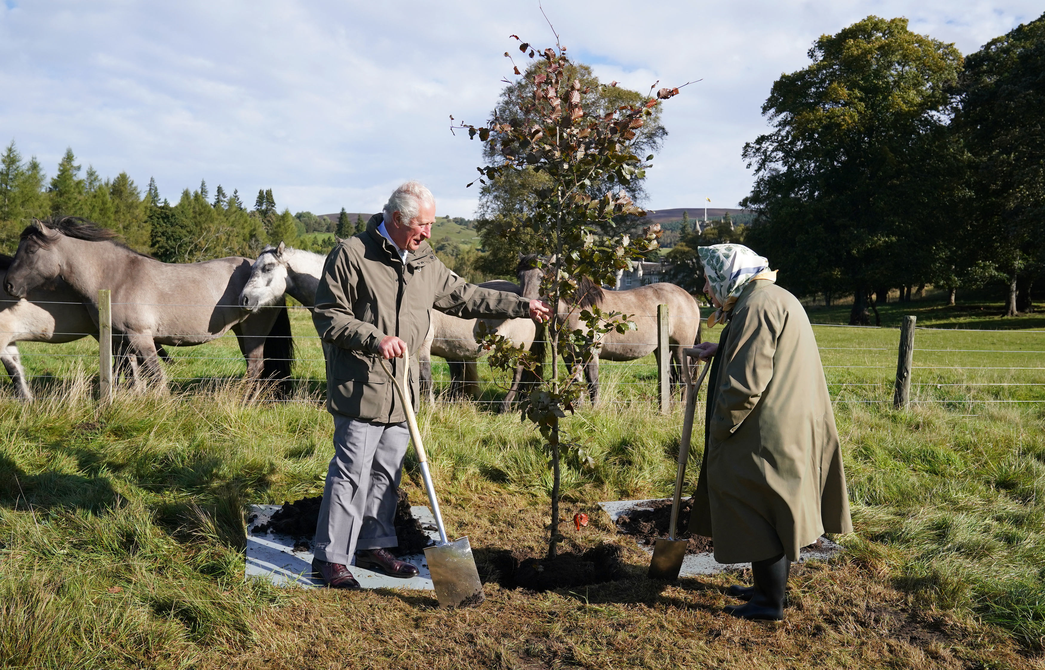 Queen Elizabeth II and then-Prince Charles plant a tree to mark the start of the official planting season for the Queen's Green Canopy at the Balmoral Cricket Pavilion, Balmoral Estate in Scotland on October 1, 2021. | Source: Getty Images