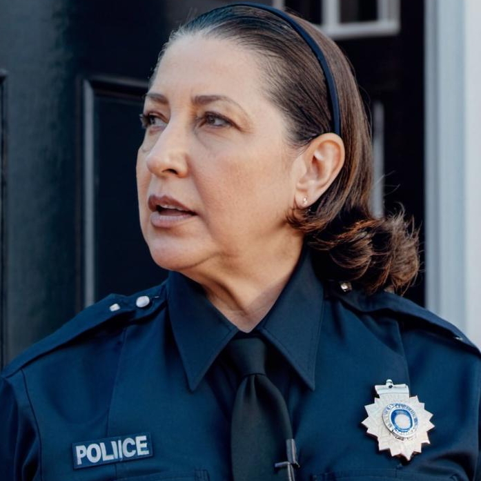 A policewoman standing outside a home's front door | Source: Midjourney