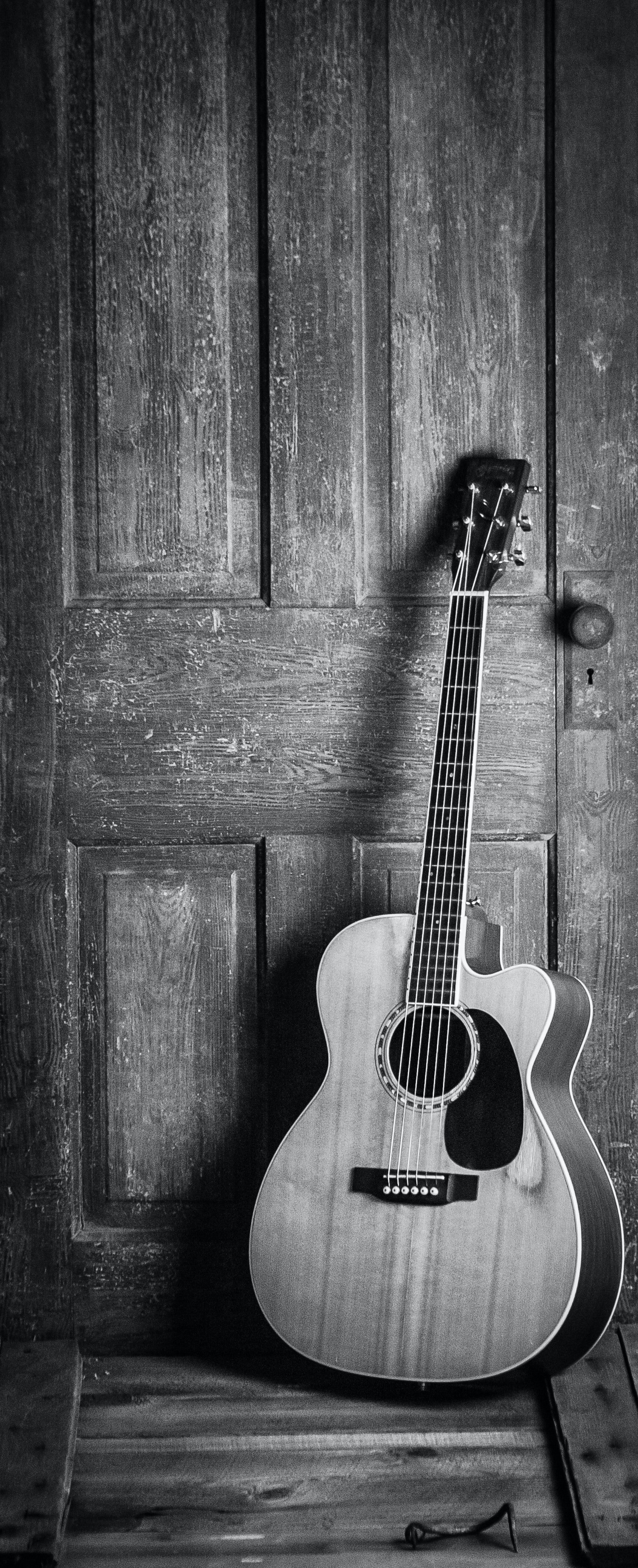 Balck and white photo of a guitar leaning against a wall. | Source: Pexels/  Jessica Lewis