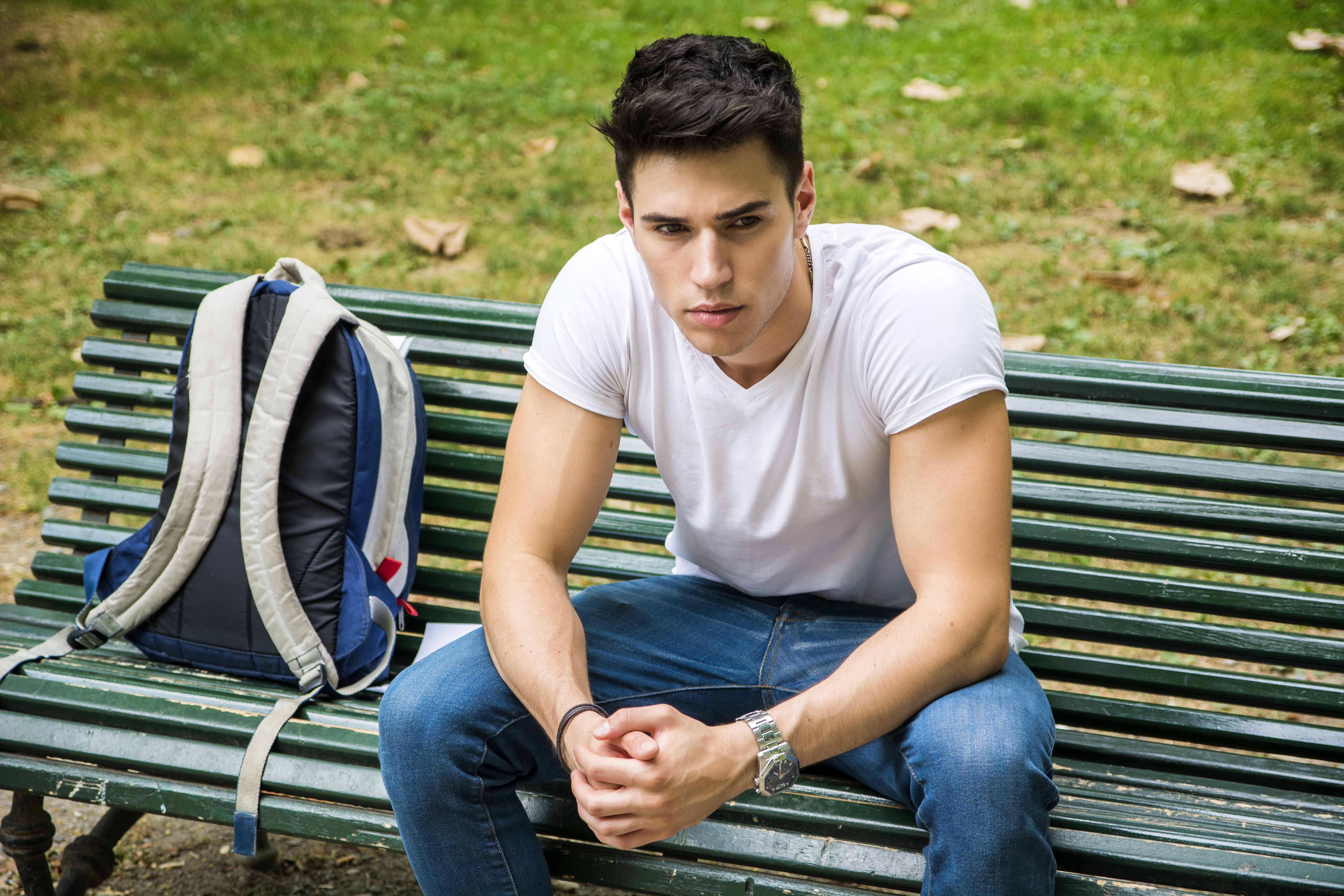 A boy sitting on a bench with his bag | Source: Shutterstock