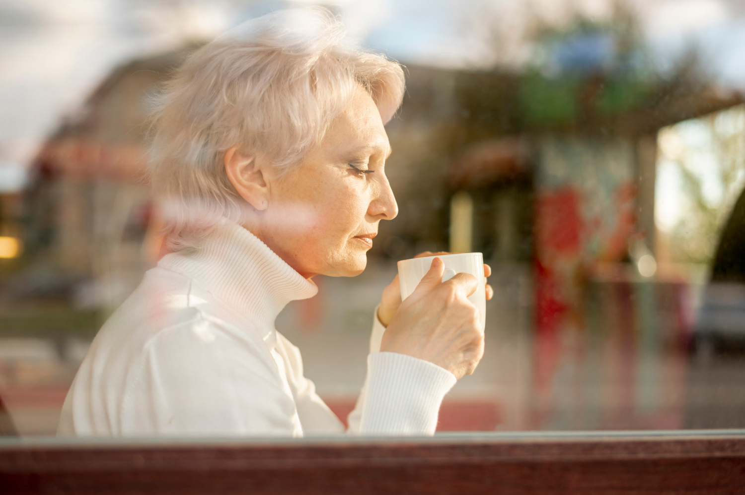 A senior woman holding a white ceramic cup | Source: Freepik