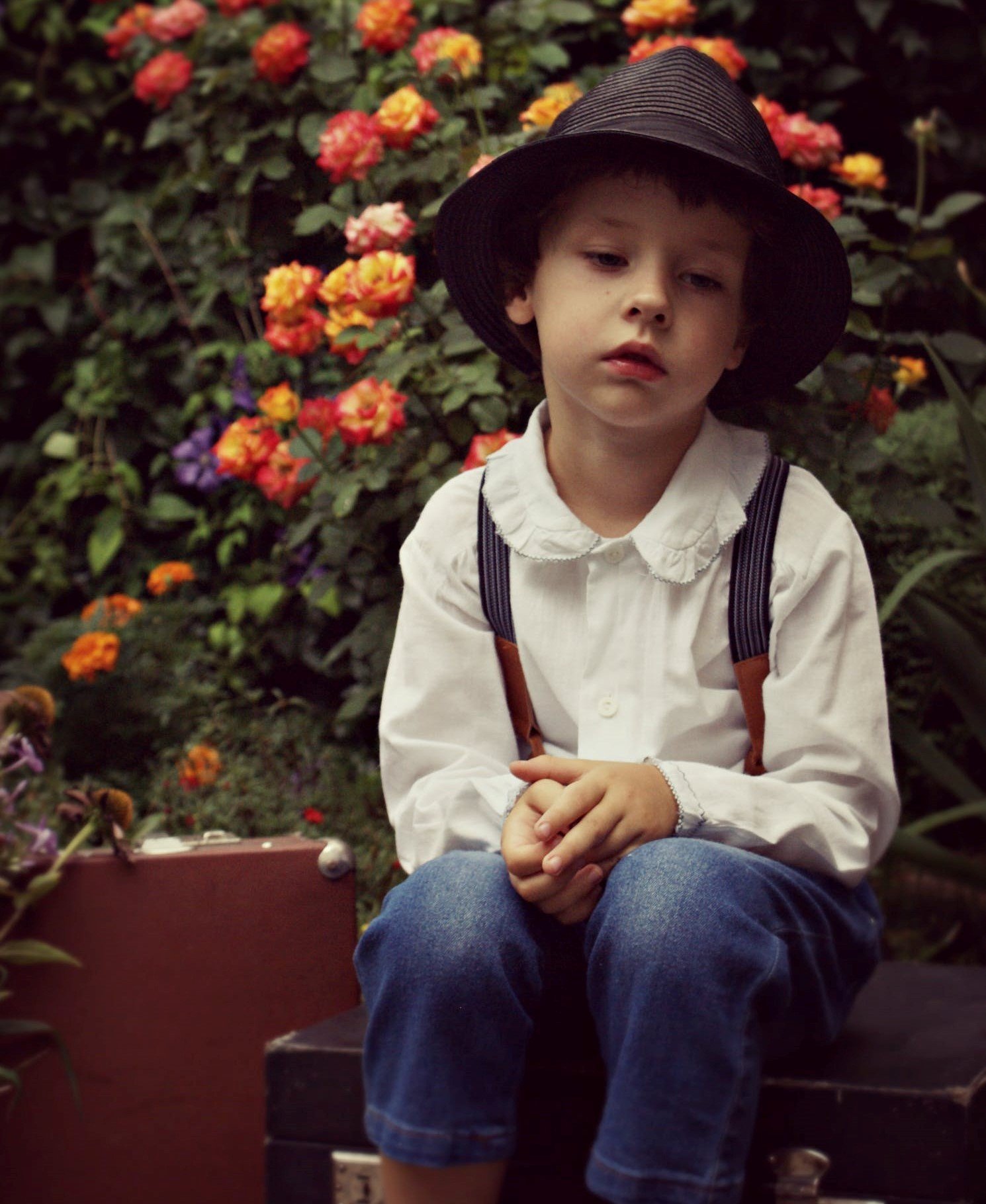 Un niño con rostro serio y un sombrero con flores en el fondo. | Foto: Pexels