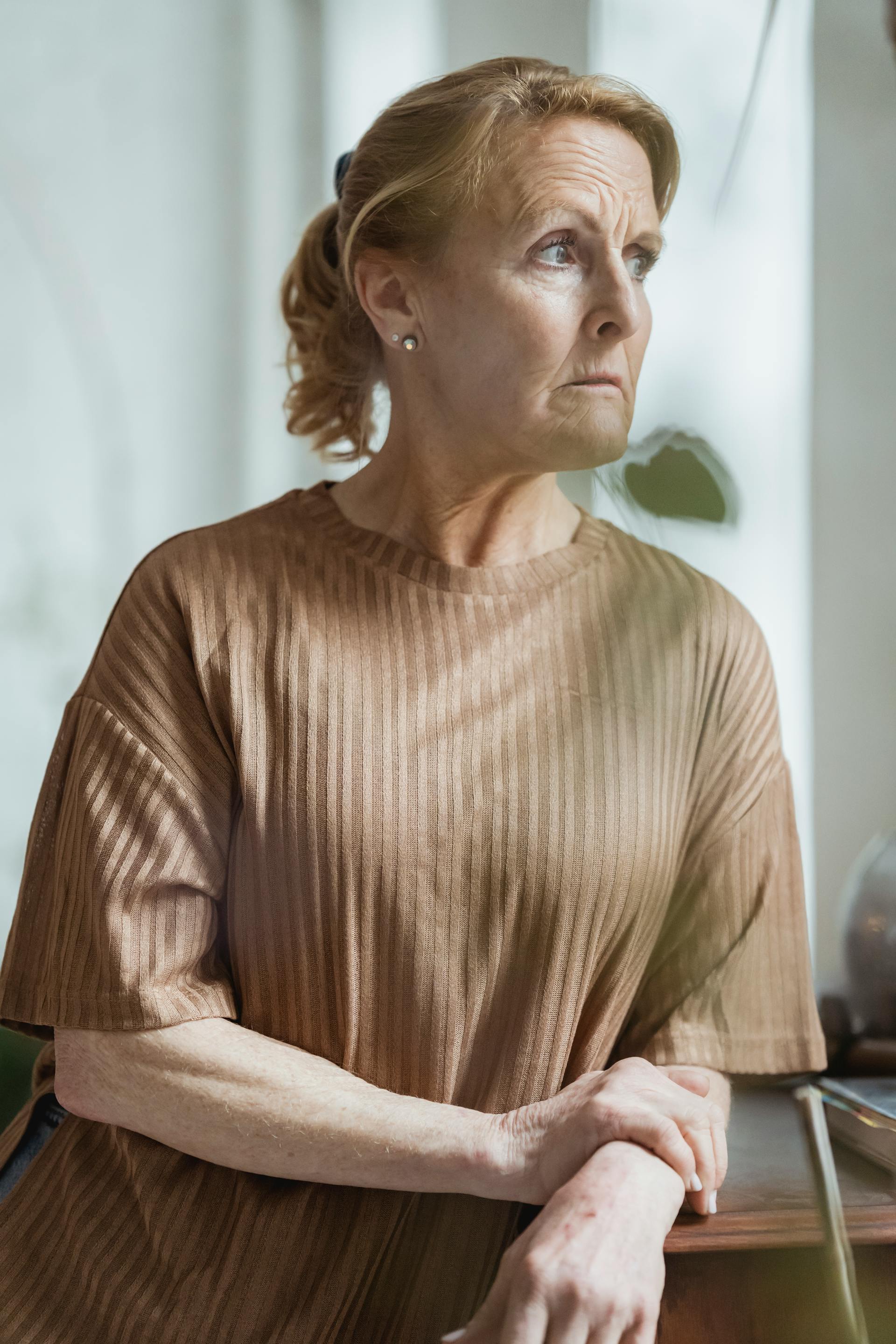 Una mujer madura con un suéter marrón y expresión preocupada, mirando hacia otro lado | Fuente: Pexels