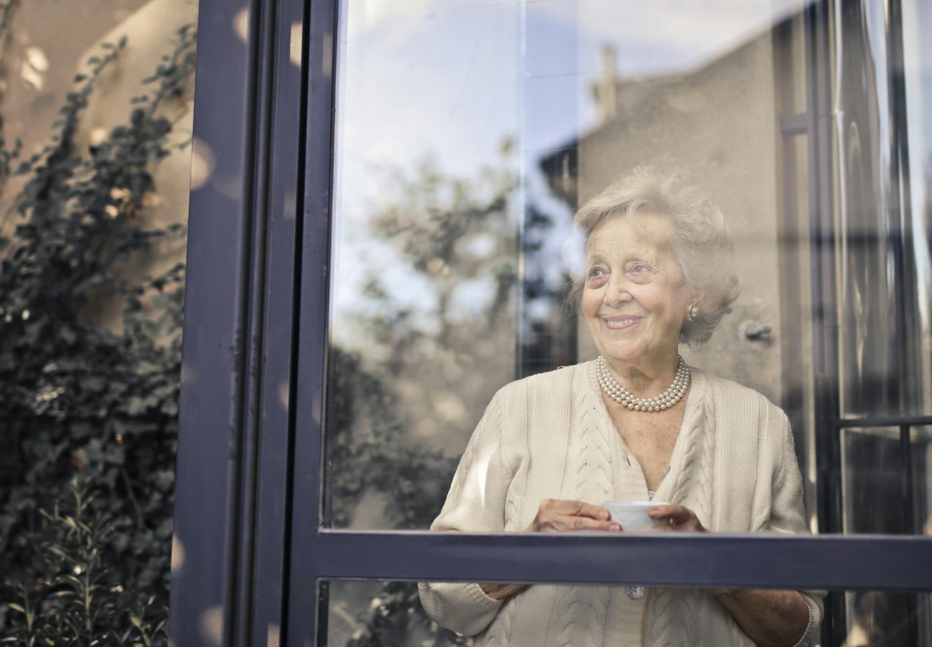 An elderly woman standing in front of a glass window | Source: Pexels