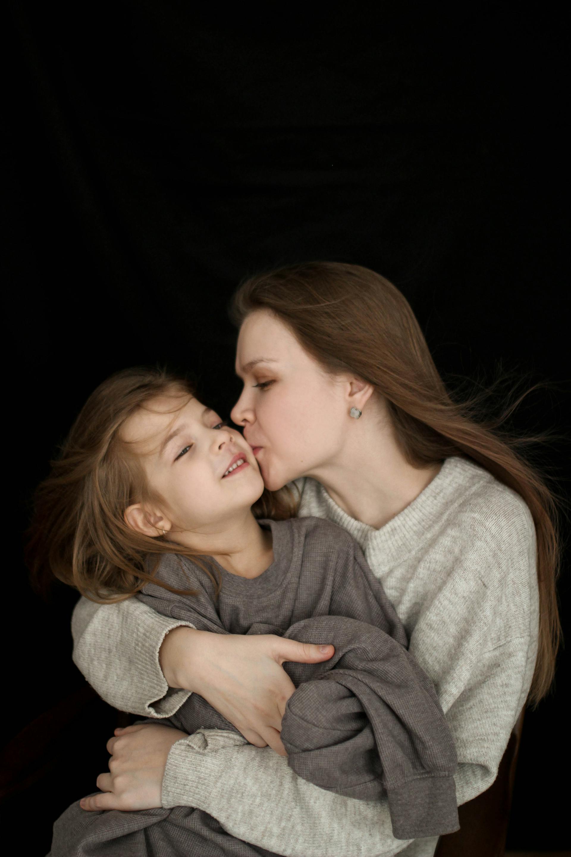 A woman kissing a young girl | Source: Pexels
