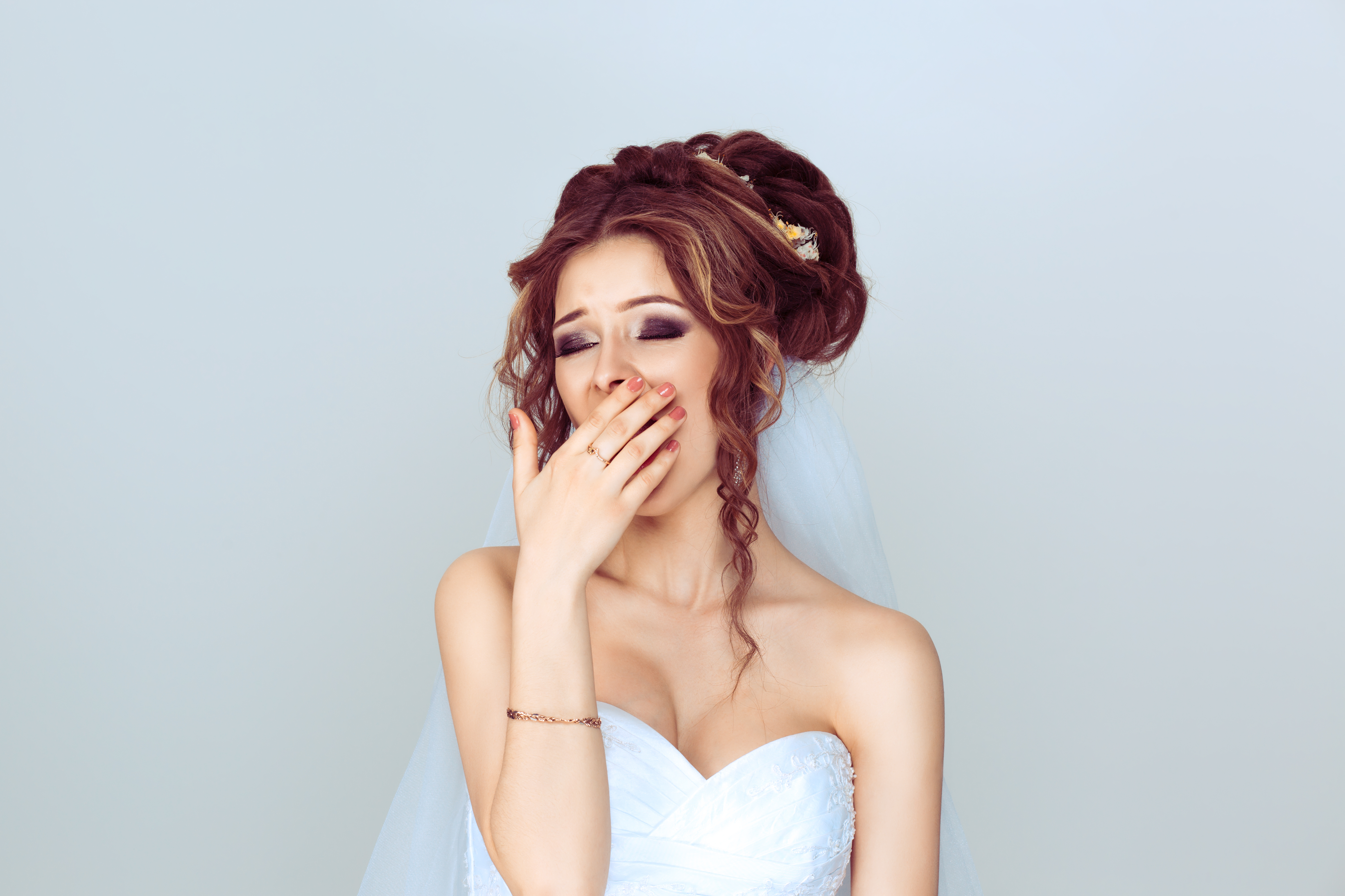 A bride covers her mouth while yawning | Source: Shutterstock
