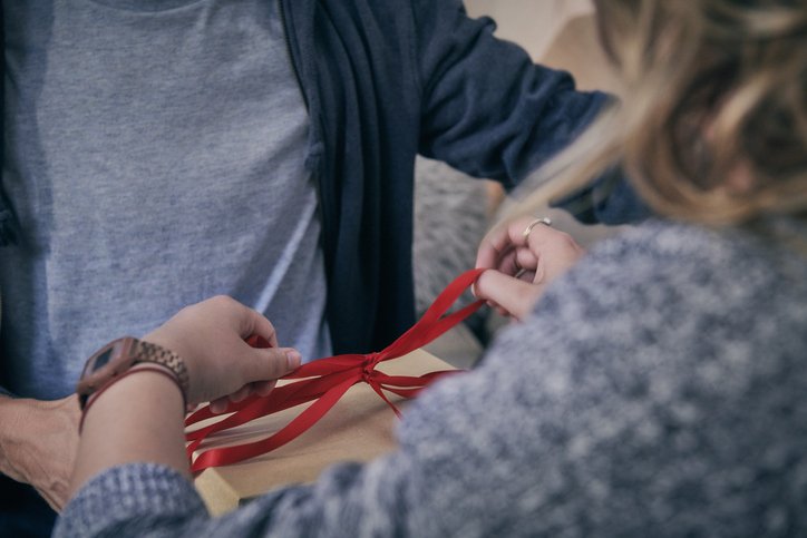 Woman tying red ribbon | Photo: Getty Images