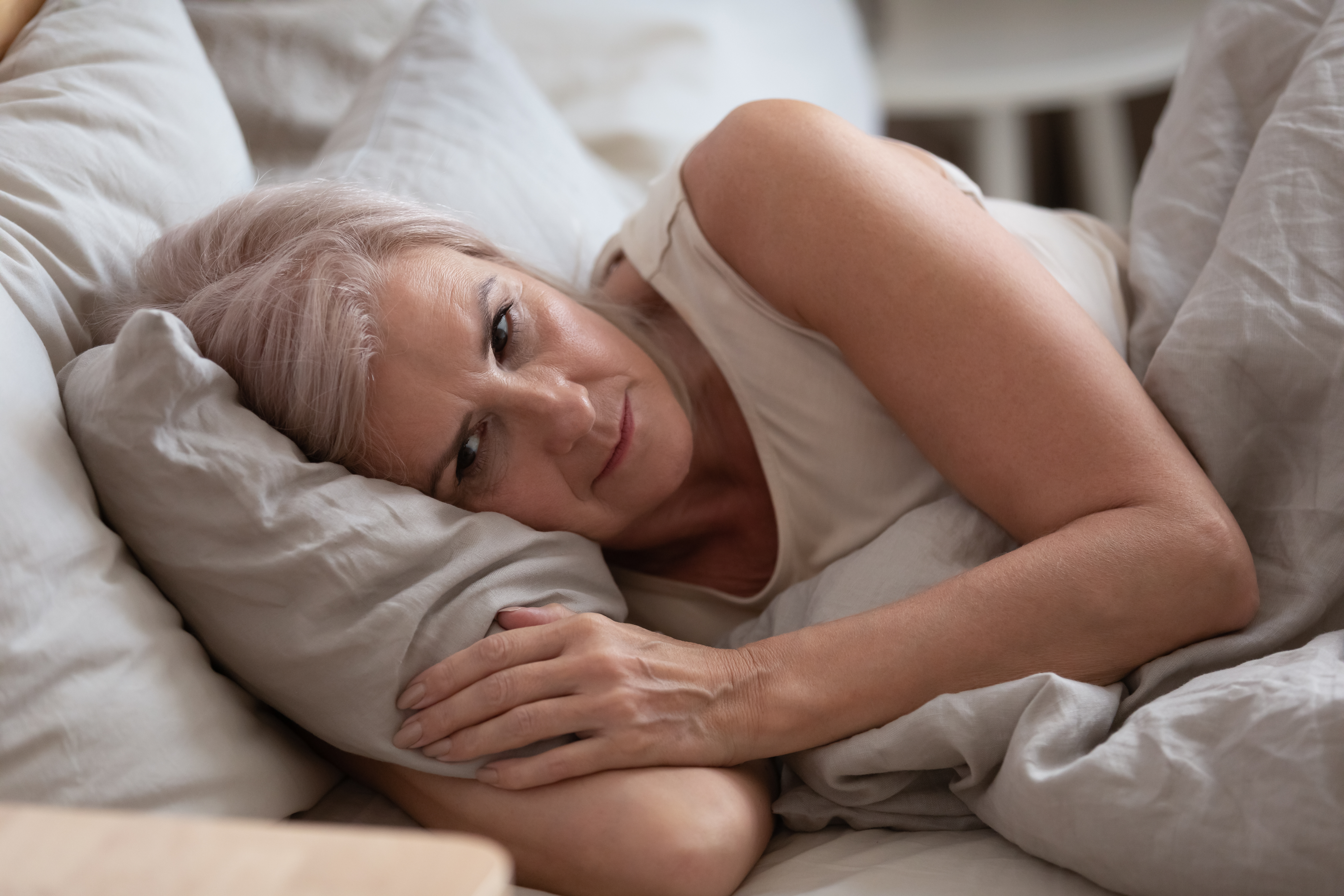 A woman in deep thought while laying in bed | Source: Shutterstock
