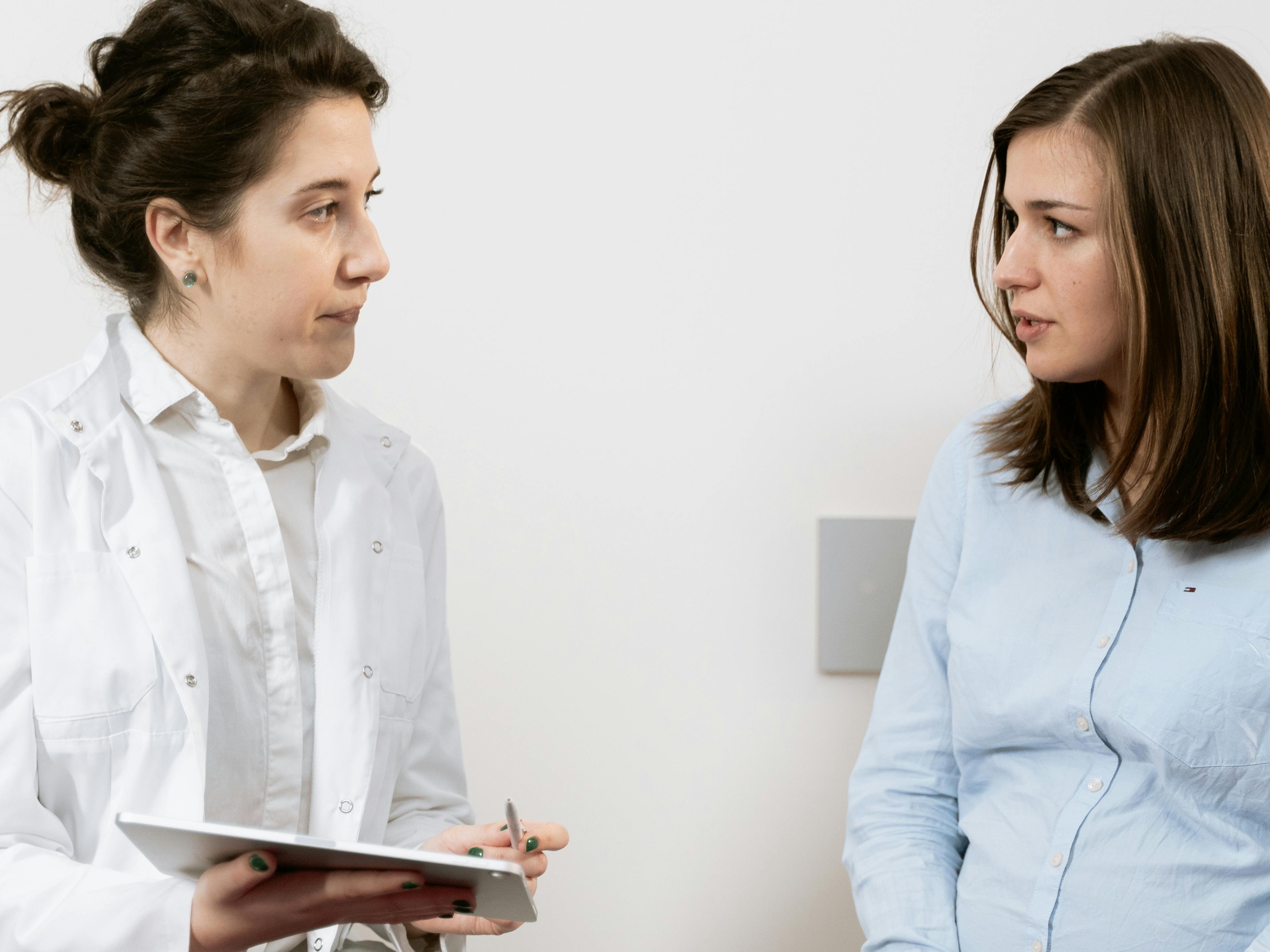 A tense patient awaits news from a somber doctor in a medical office | Source: Midjourney