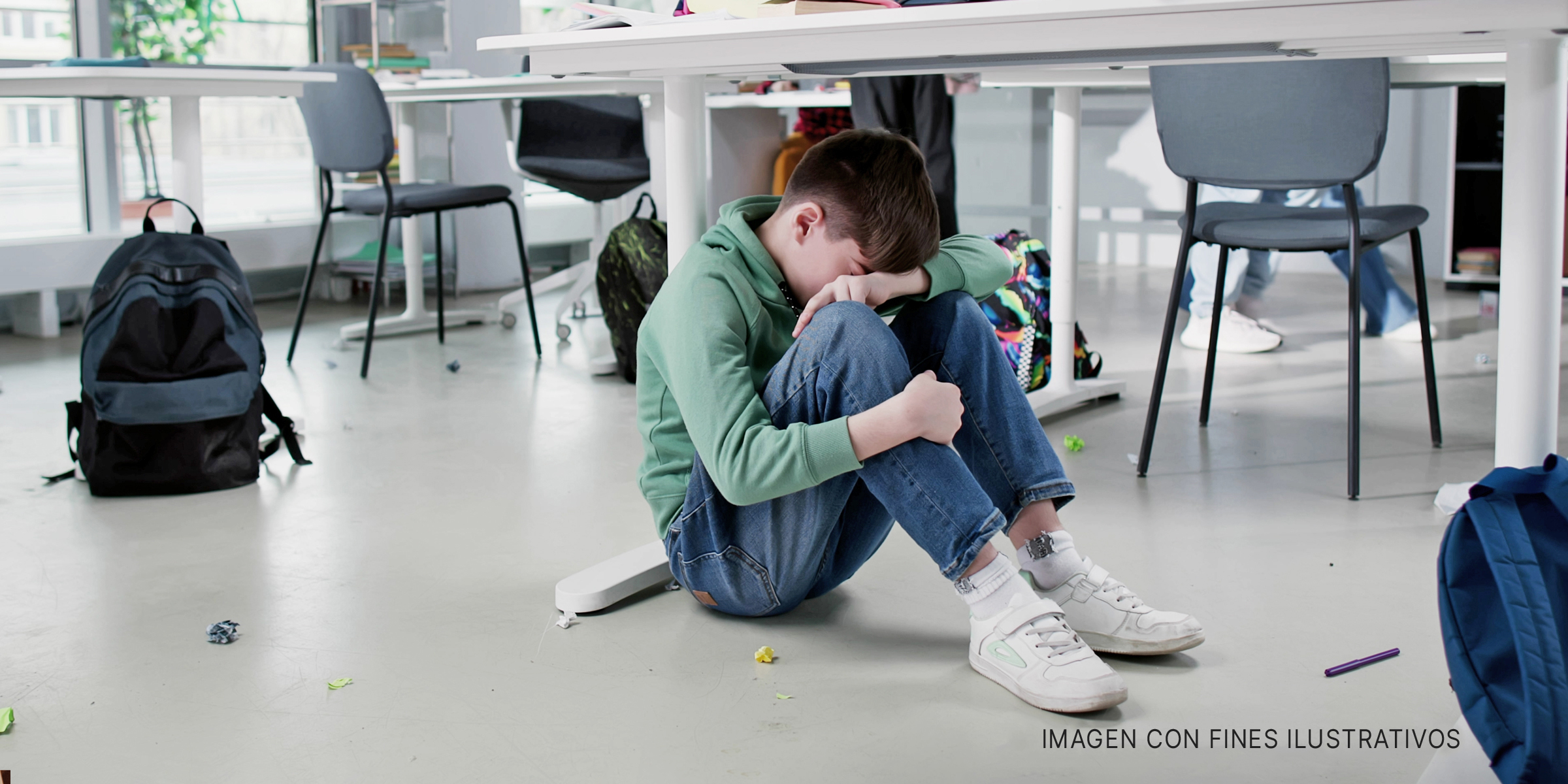 Chico llorando en el suelo de un salón de clases. | Foto: Shutterstock