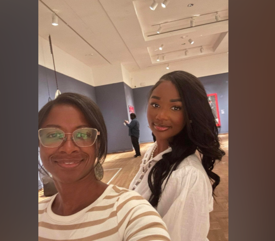 Ashly Robinson shares a warm, candid moment with a loved one, their smiles soft and genuine against the calm backdrop of a gallery space. | Source: Gofundme