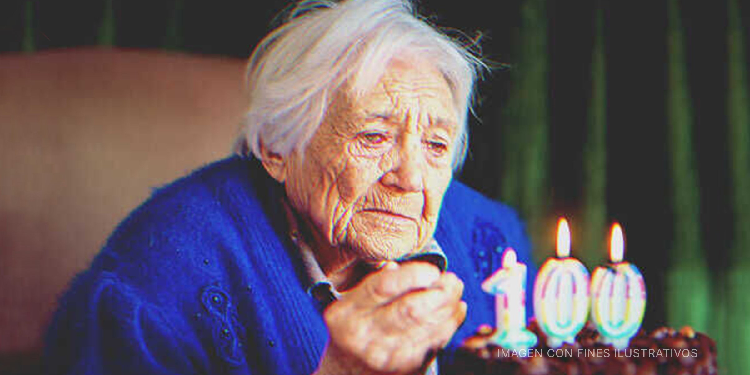 Anciana mira a pastel de cumpleaños con velas en forma de 100 | Foto: Getty Images