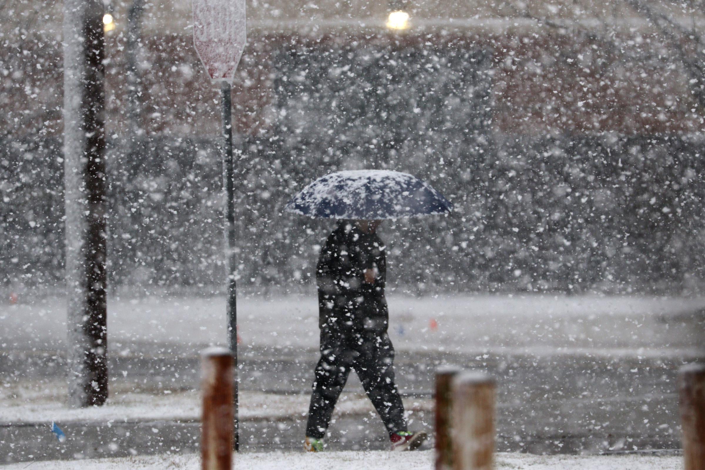 A man walks on the snow-covered sidewalk as snow falls in Norman, Oklahoma, on January 24, 2023 | Source: Getty Images