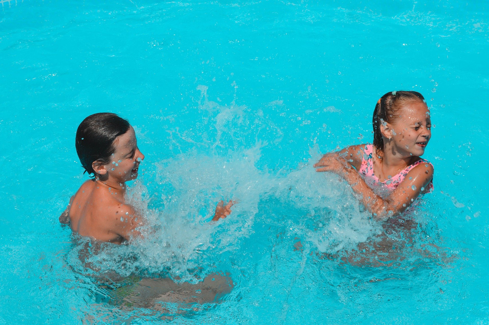 Two kids splashing water in the pool | Source: Pixabay